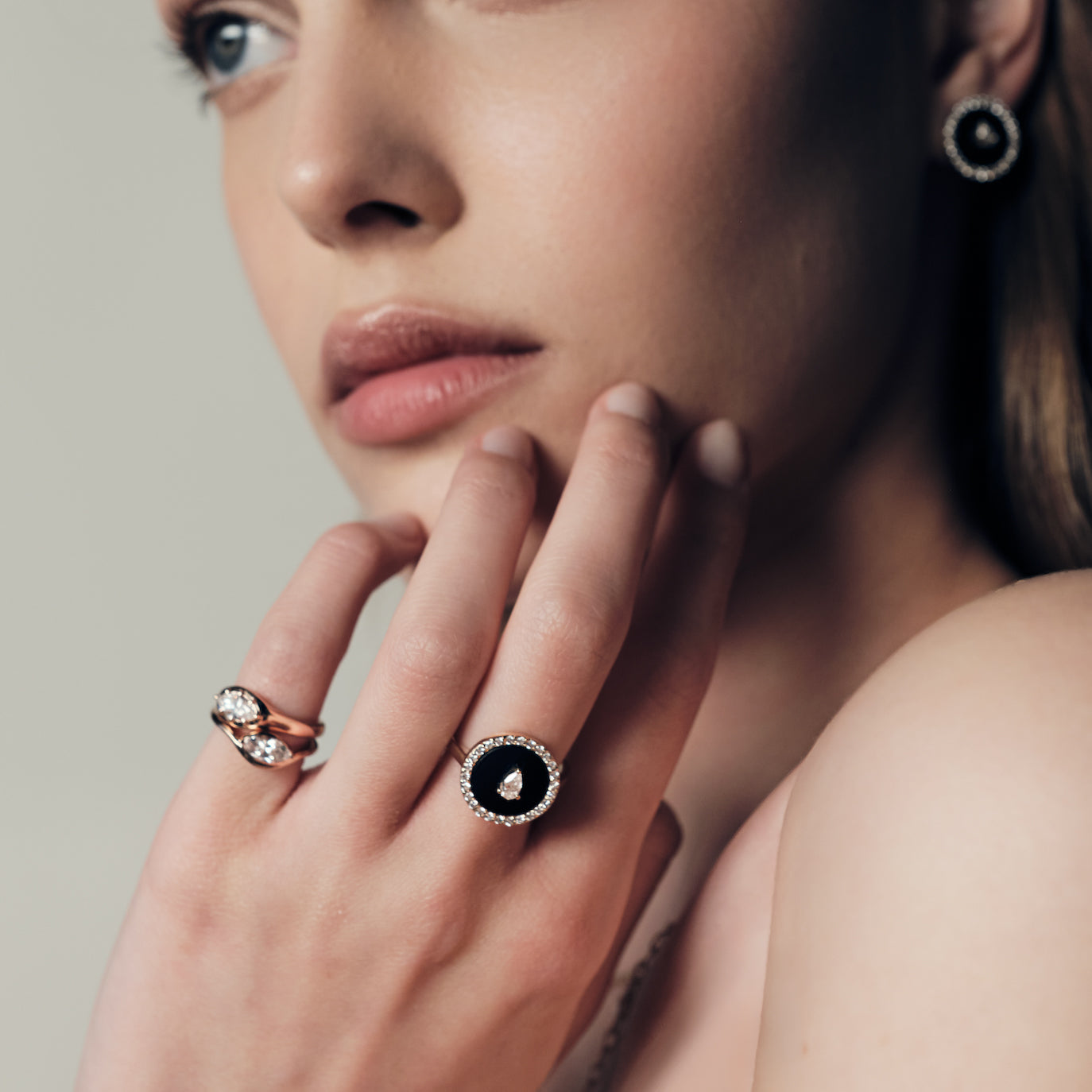 A woman wearing a ring with a black onyx and diamonds, two pinky ring with marquise diamonds set in curvy rose gold bands.