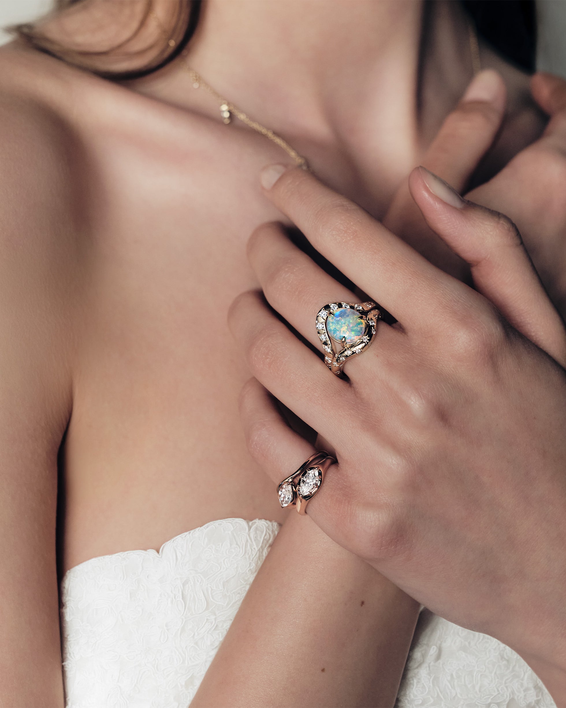 A woman wearing a ring with a australian opal and diamonds, two pinky ring with marquise diamonds set in curvy rose gold bands.