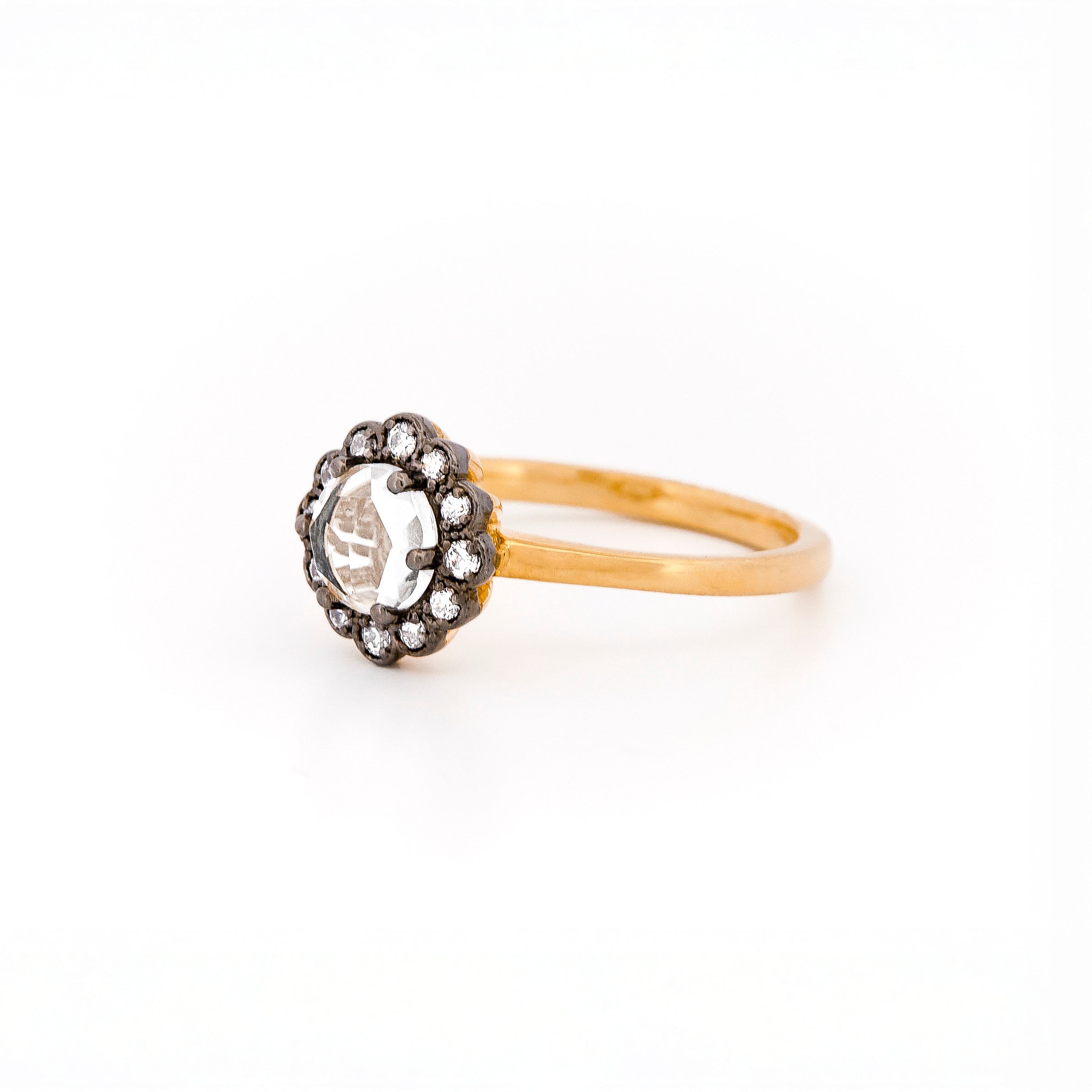 Rose gold ring with a large central rose cut diamond and smaller stones, set in black rhodium plated gold, on a white background