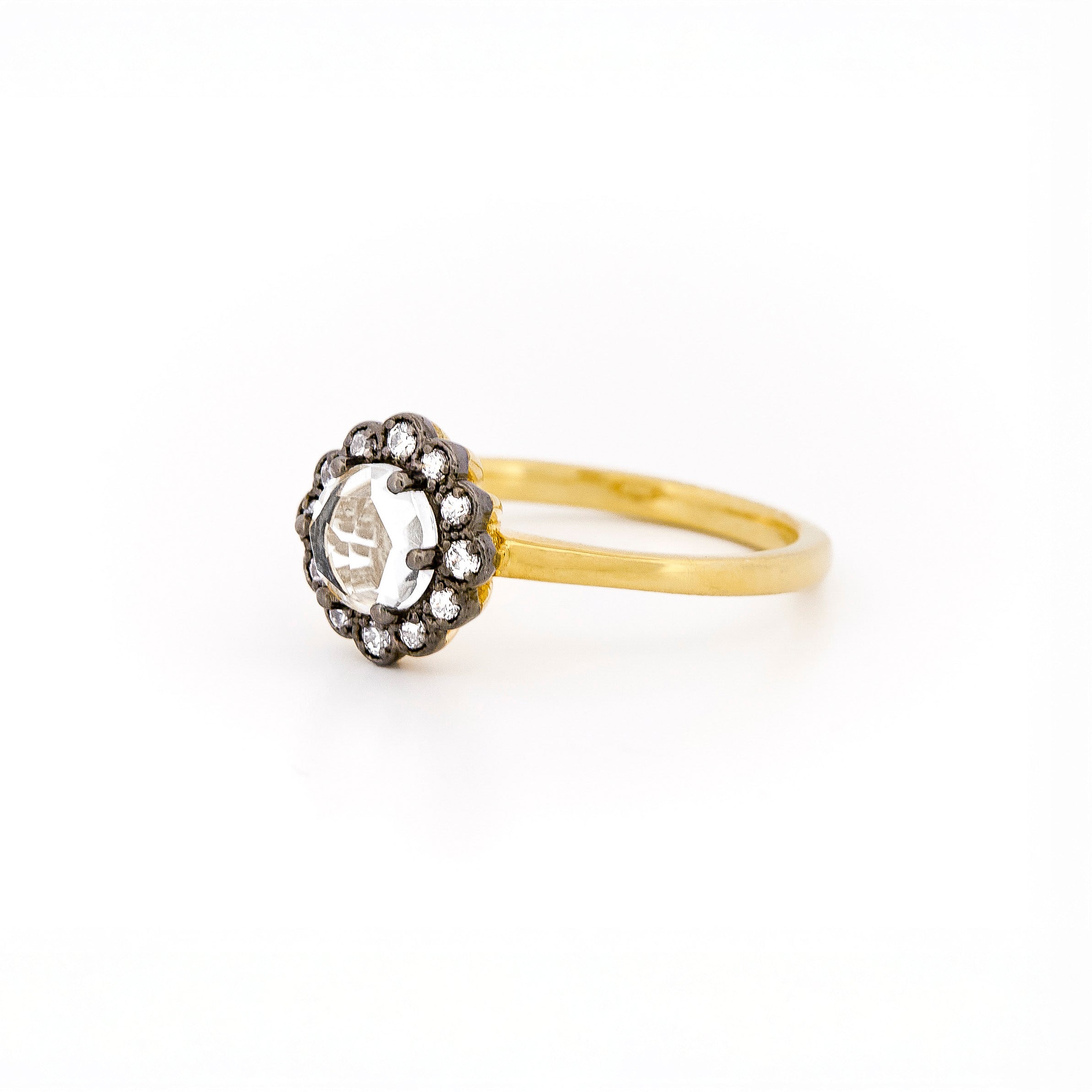 Yellow gold ring with a large central rose cut diamond and smaller stones, set in black rhodium plated gold, on a white background