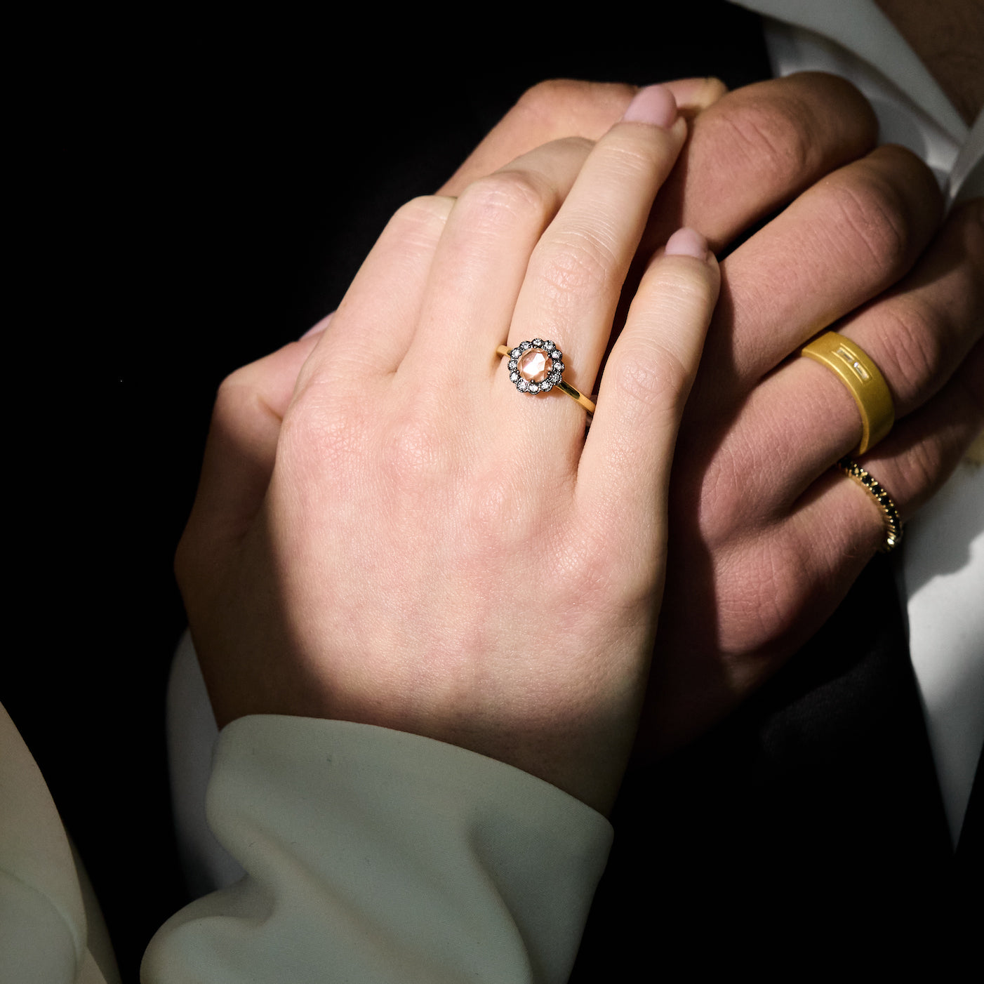 Close-up of two hands holding each other, one wearing a gold ring with a diamond.