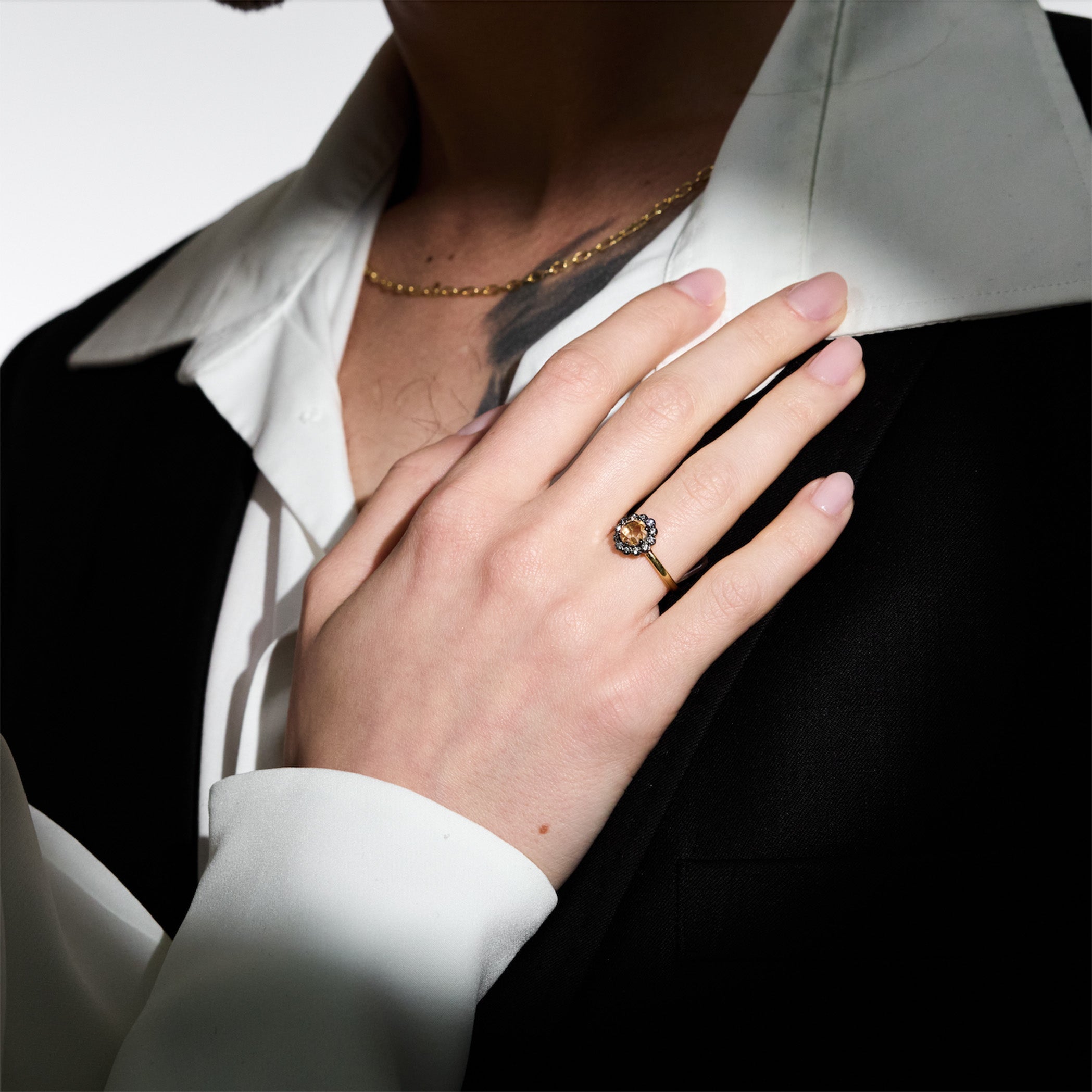 Hand wearing a ring with a visible rose cut diamond, resting her hand on her husband's chest