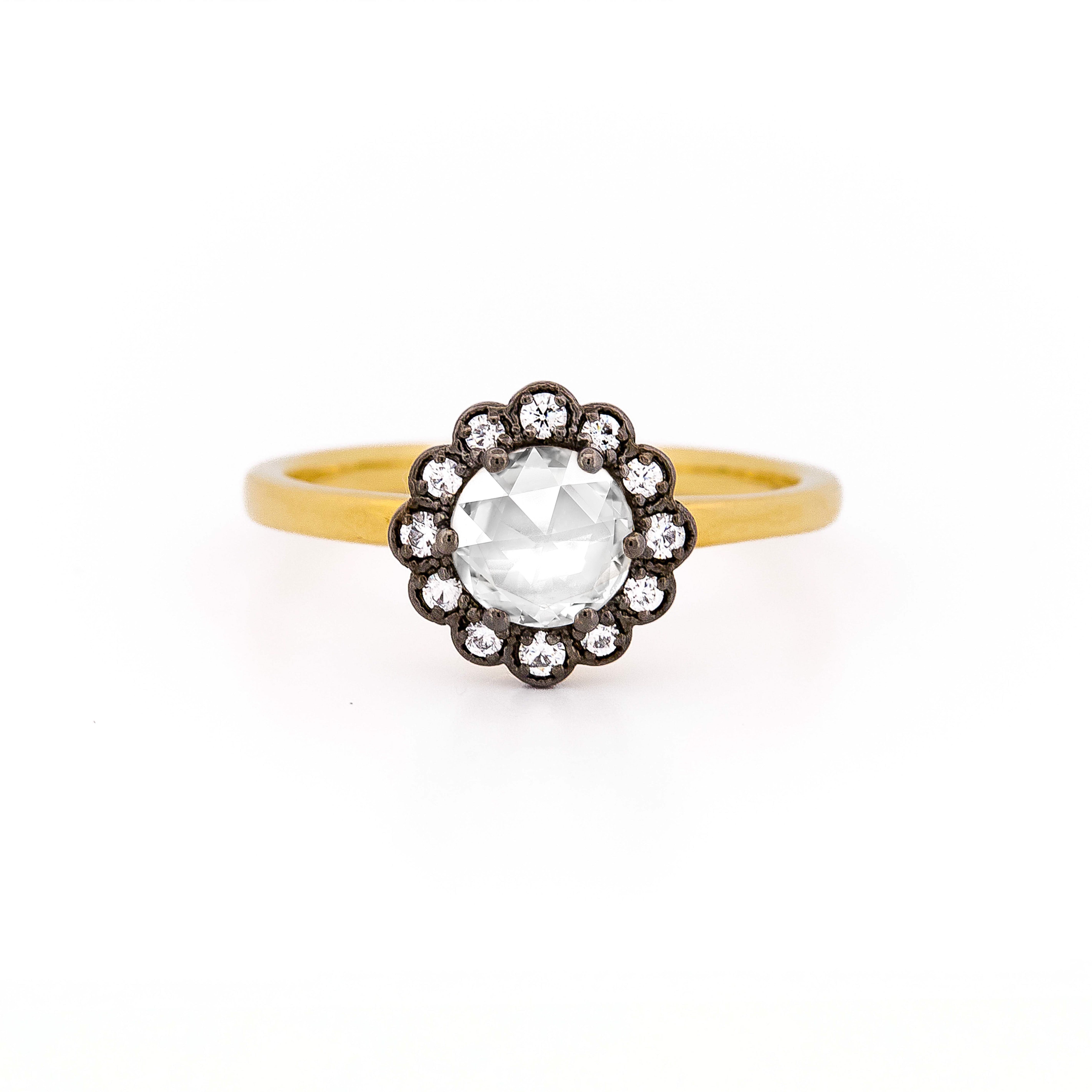 Gold ring with a central diamond surrounded by black plated gold and smaller diamonds on a white background