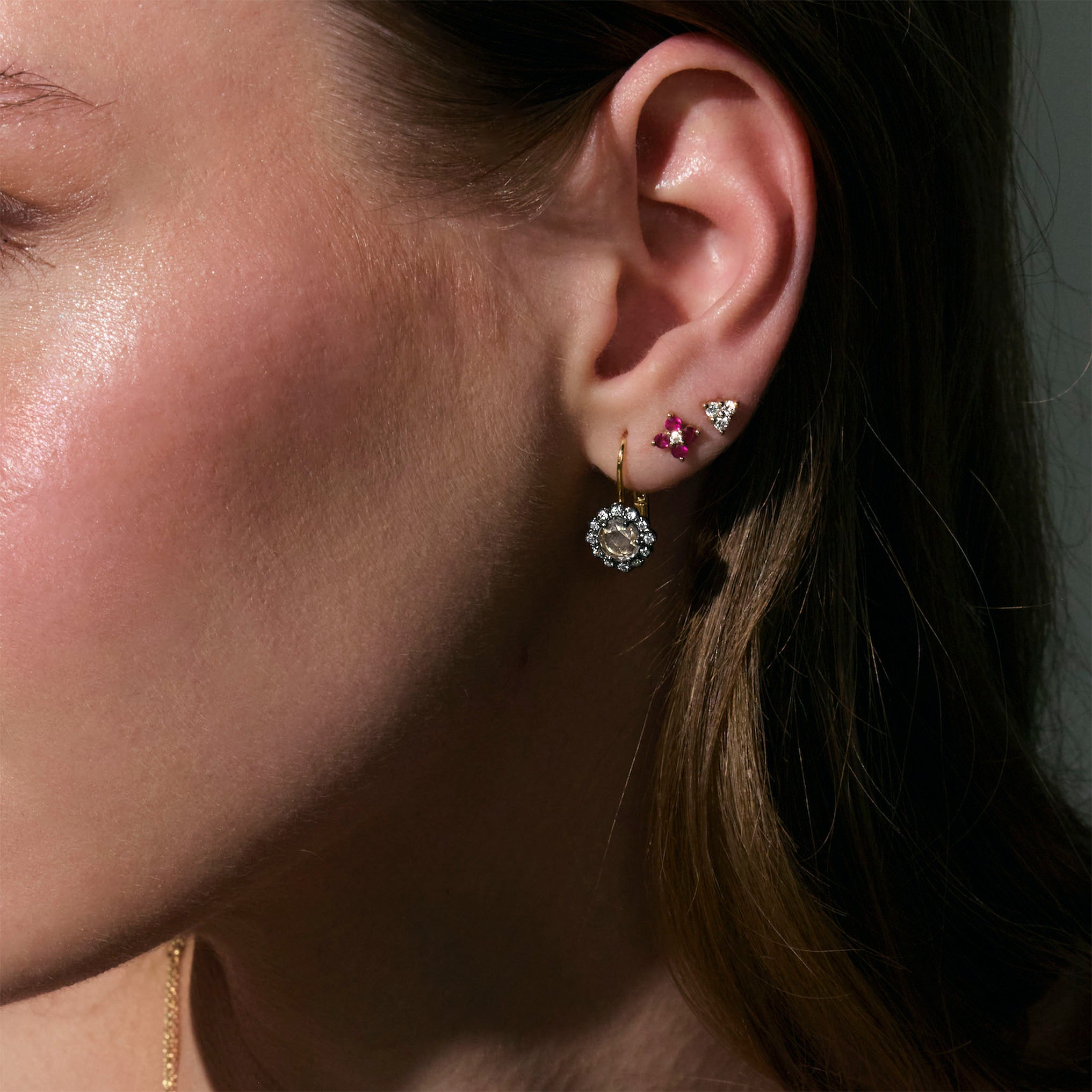 beautiful rose cut diamonds earrings, set in black rhodium 14k or 18k gold, and a dainty trilogy diamonds stud earring on models ear