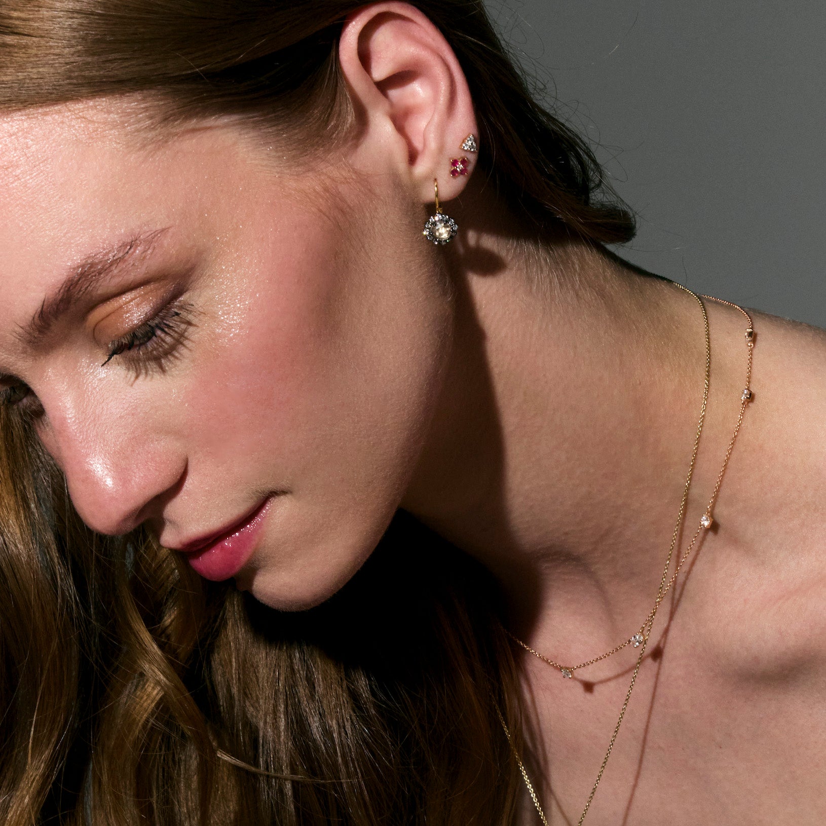 beautiful rose cut diamonds earrings, set in black rhodium 14k or 18k gold, and a dainty dot dot dot diamonds stud earring, and a ruby sparks earring on models ear