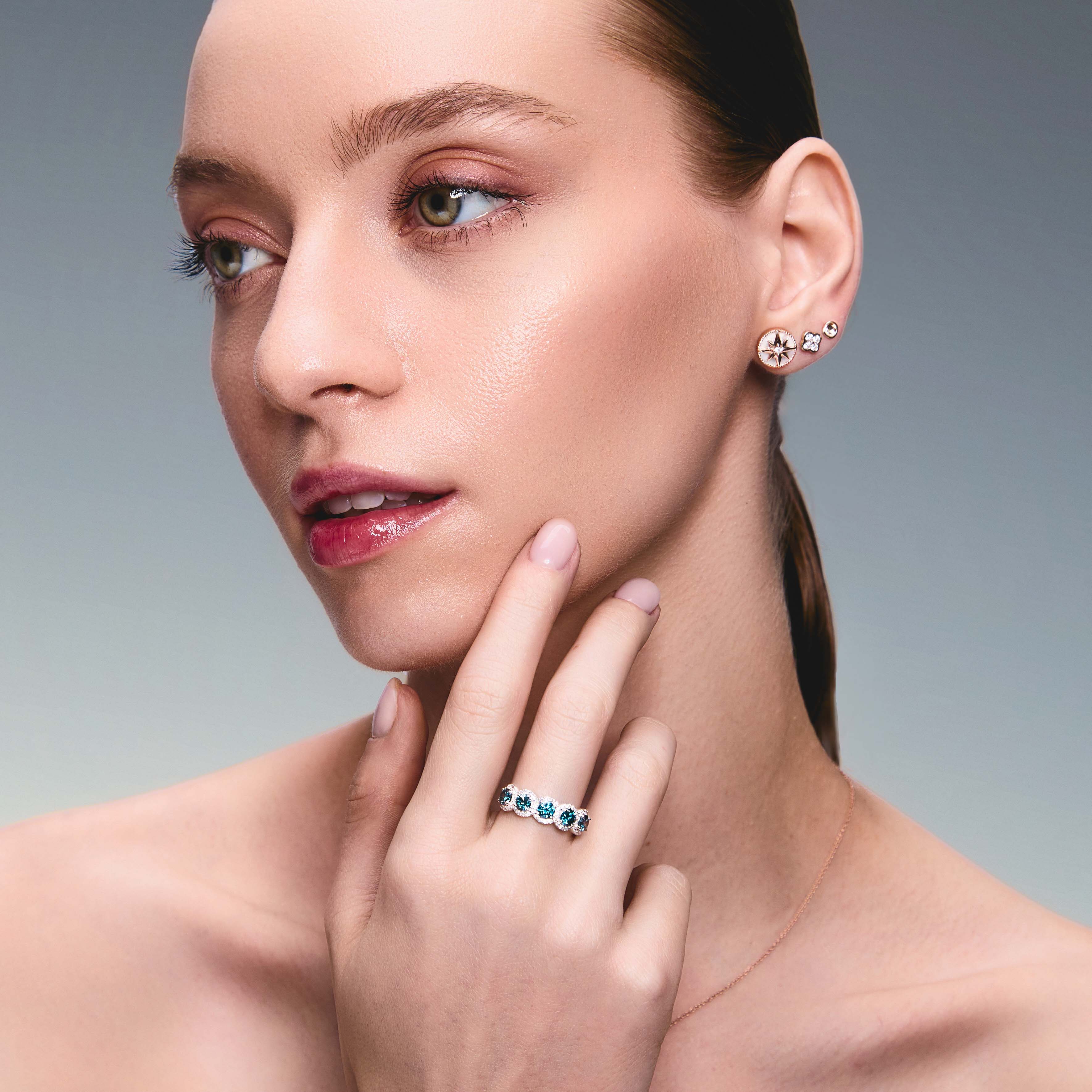Beautiful model wearing some incredible stud earrings, one is symbolising the north star, the second earring is a diamond clover and the third earring in a simple gold scoop earring. The girl is also wearing a mesmerising blue lab diamonds ring that is absolutely breathtaking.