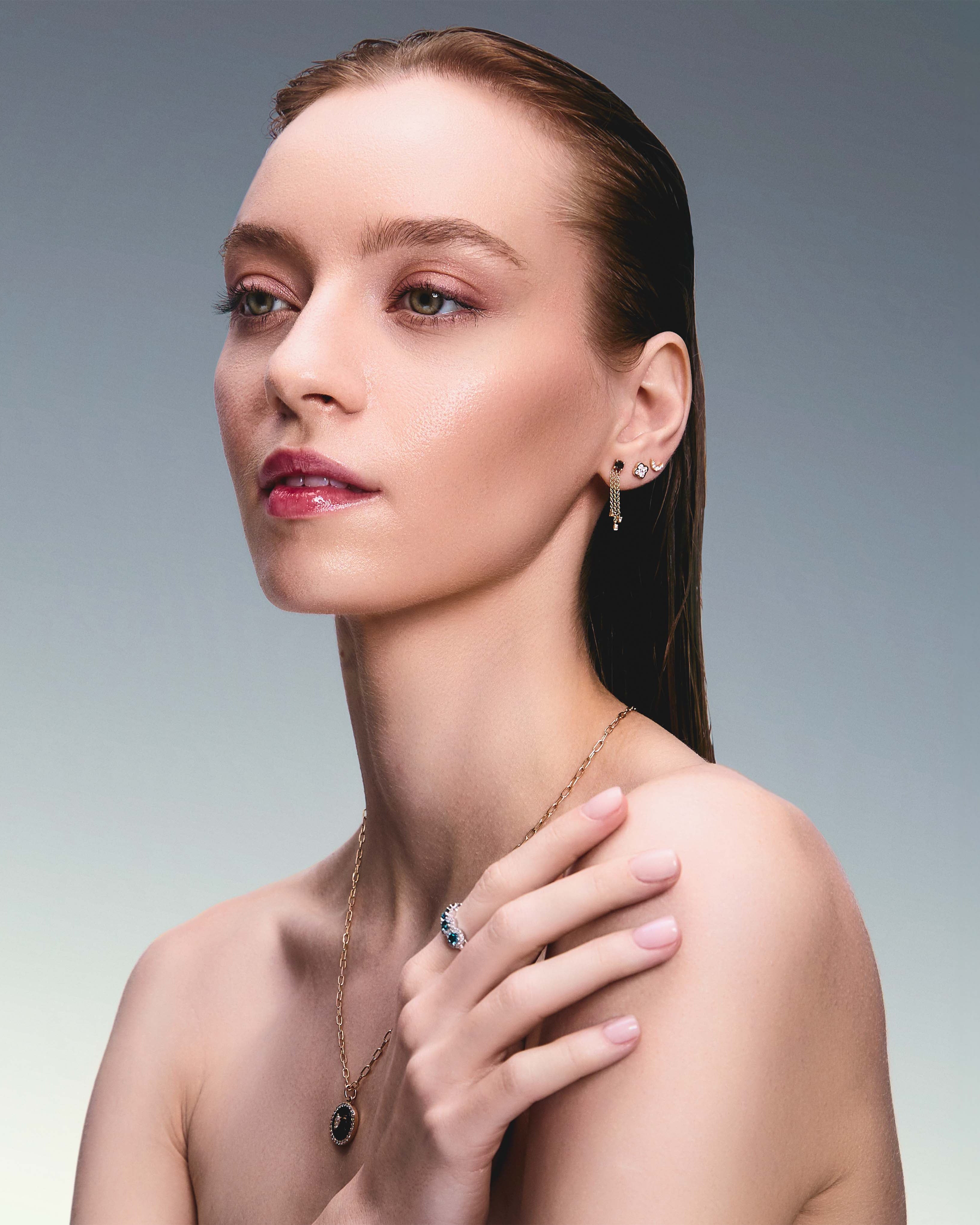 Beautiful model wearing some incredible stud earrings, one is a trilik hanging earring with black diamonds, the second earring is a diamond clover and the third earring in a diamond new moon.