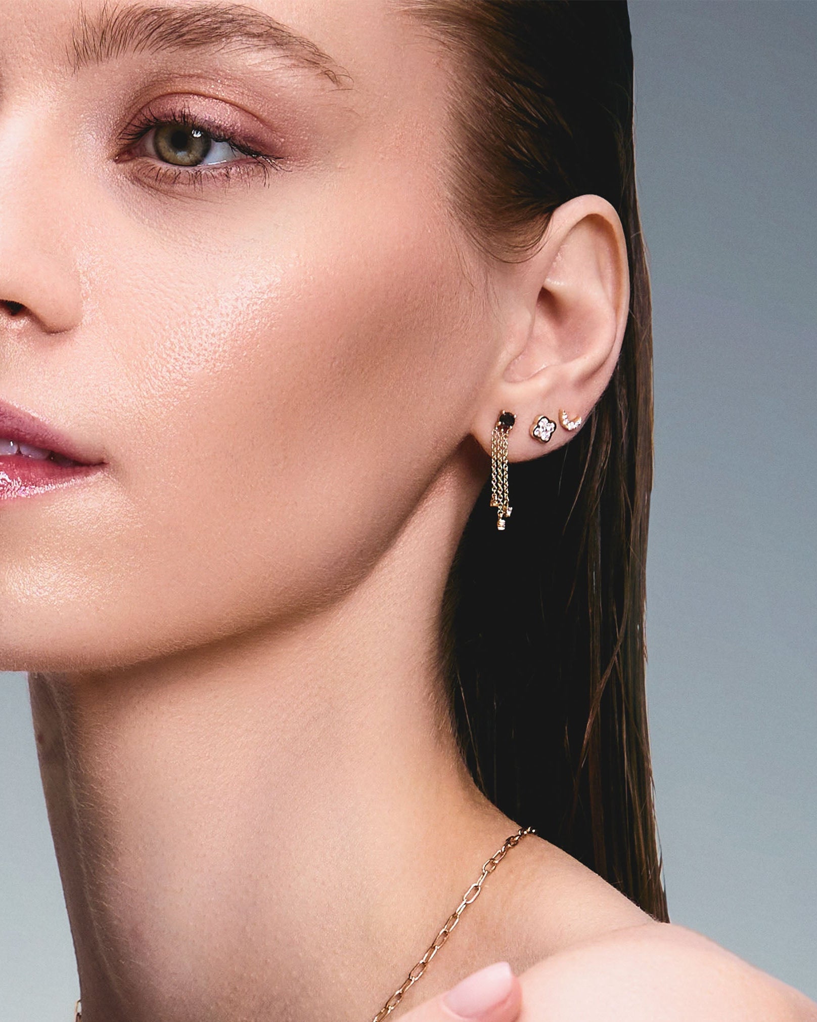 Beautiful model wearing some incredible stud earrings, one is a trilik hanging earring with black diamonds, the second earring is a diamond clover and the third earring in a diamond new moon.