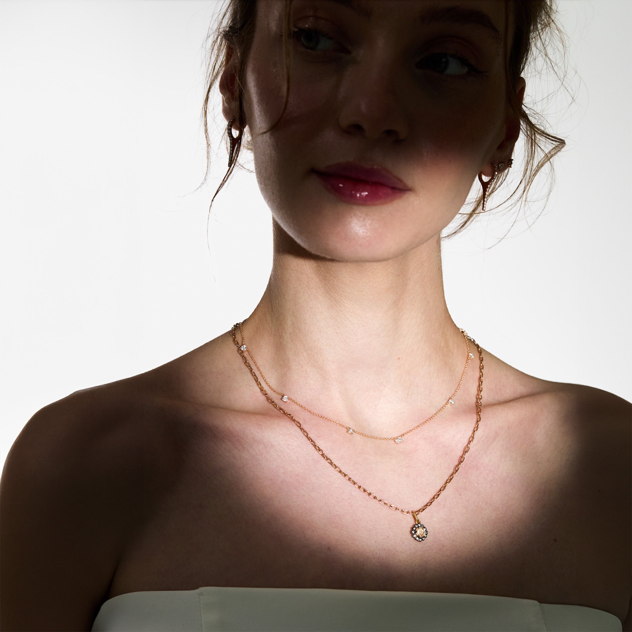 Woman wearing a delicate necklace with a small pendant on a plain background