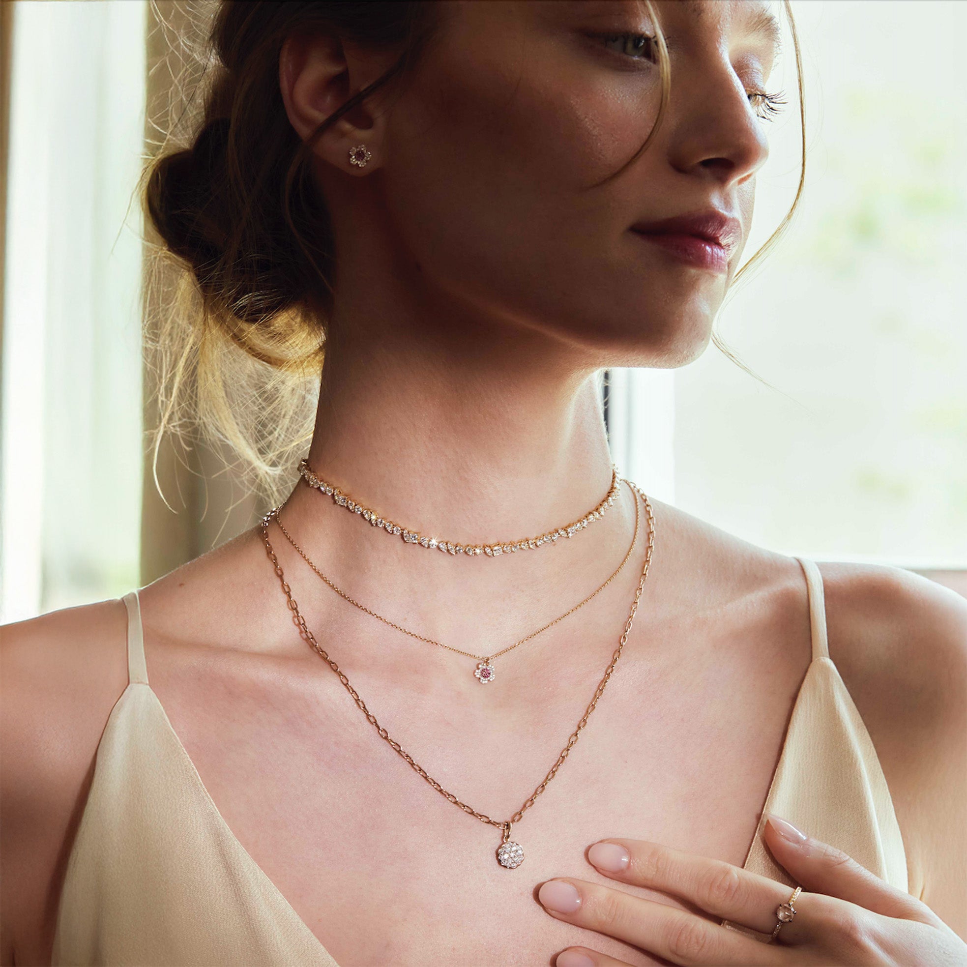 Woman wearing multiple diamonds necklaces, and flower earrings with a soft background
