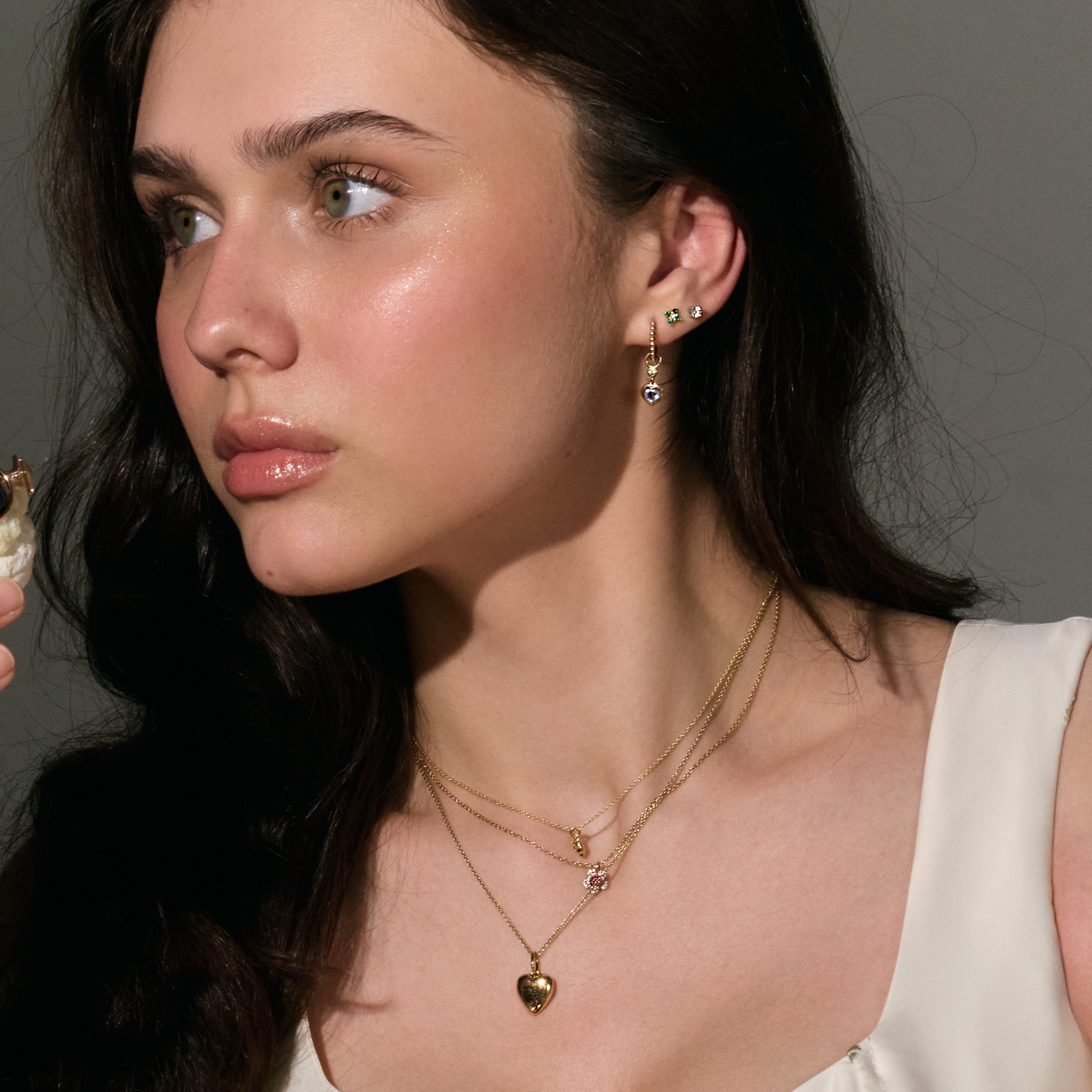 Woman wearing gold necklaces and earrings against a neutral background
