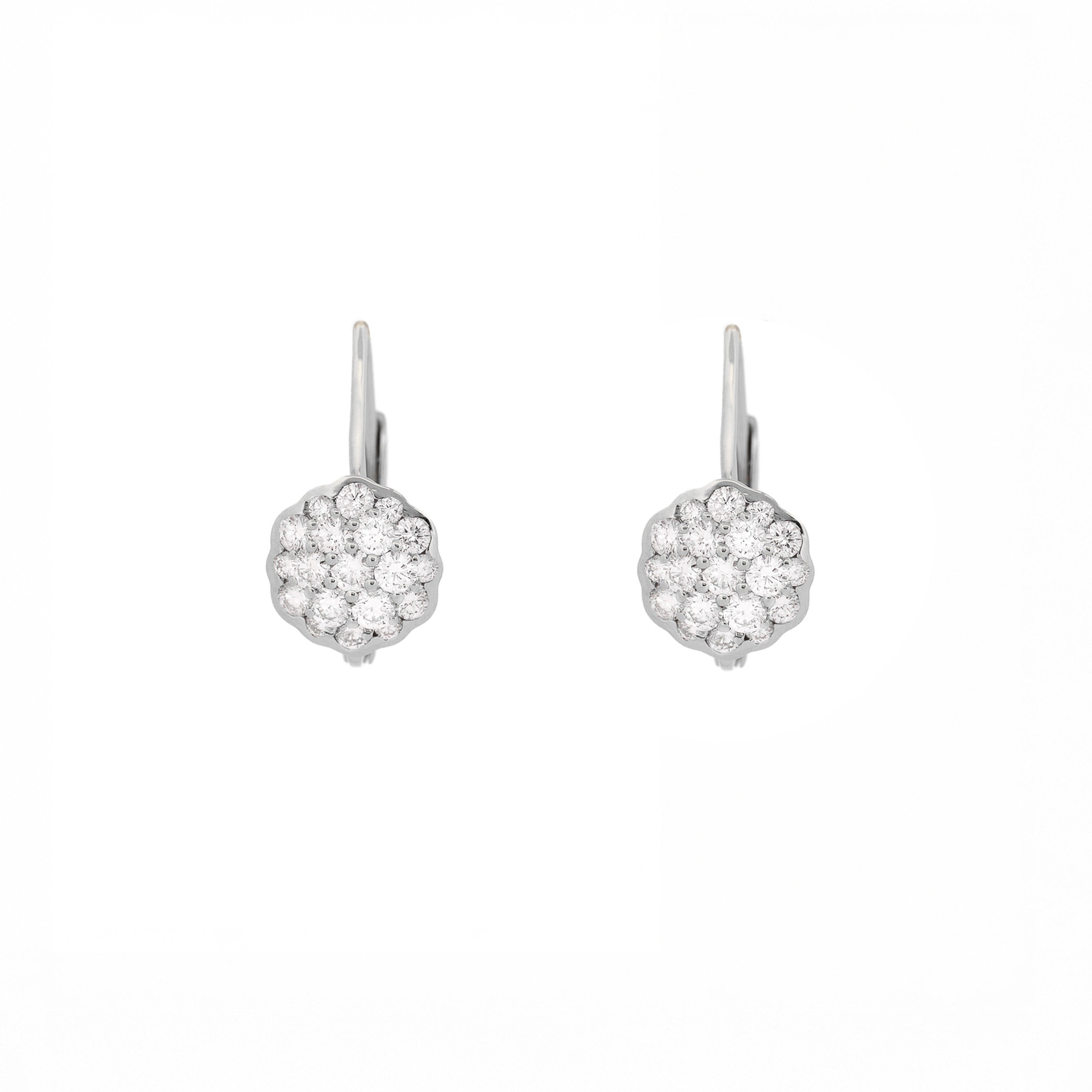 Pair of white gold earrings with a flower made of diamonds on a white background