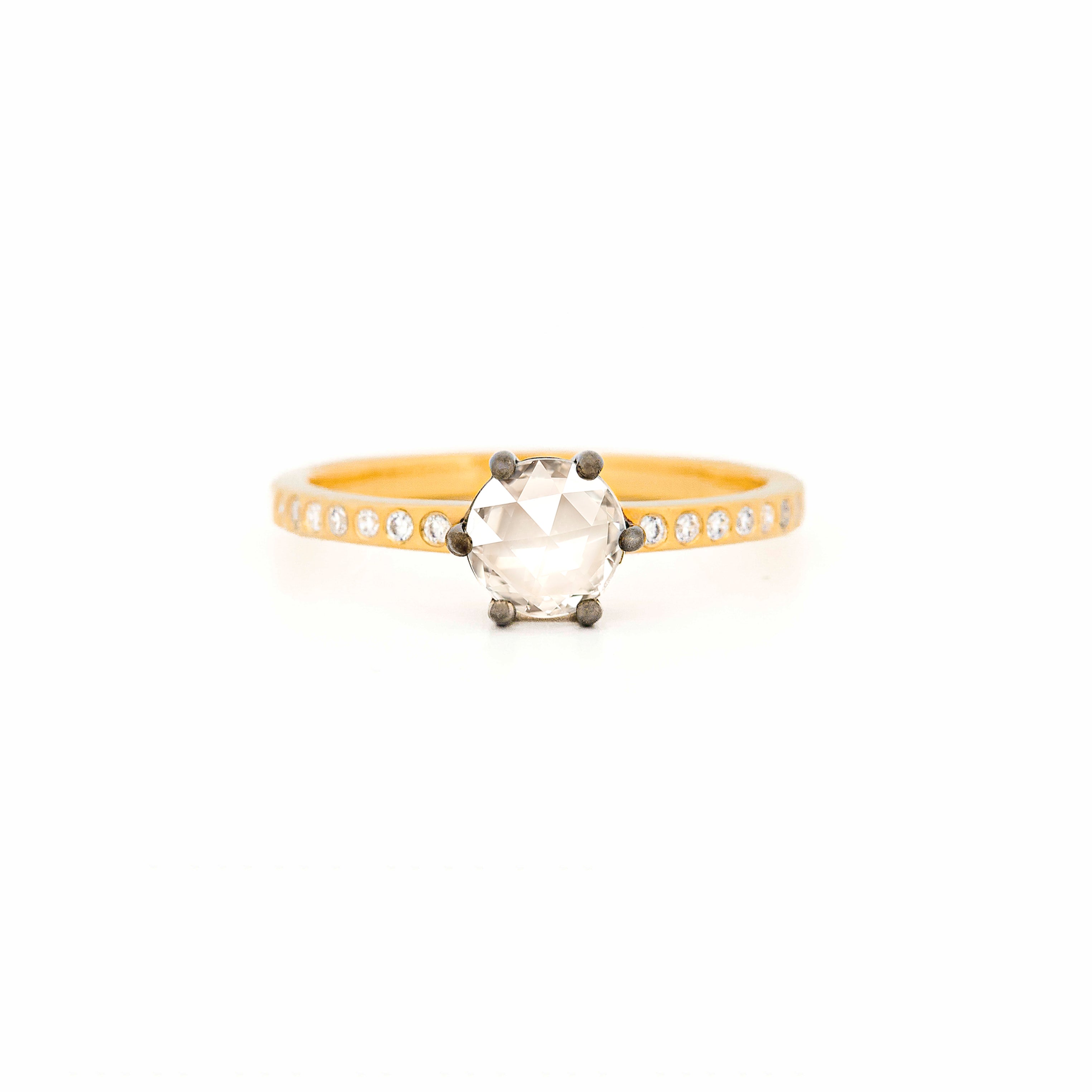 Ring with a large central rose-cut diamond and smaller side diamonds on a yellow gold band against a white background