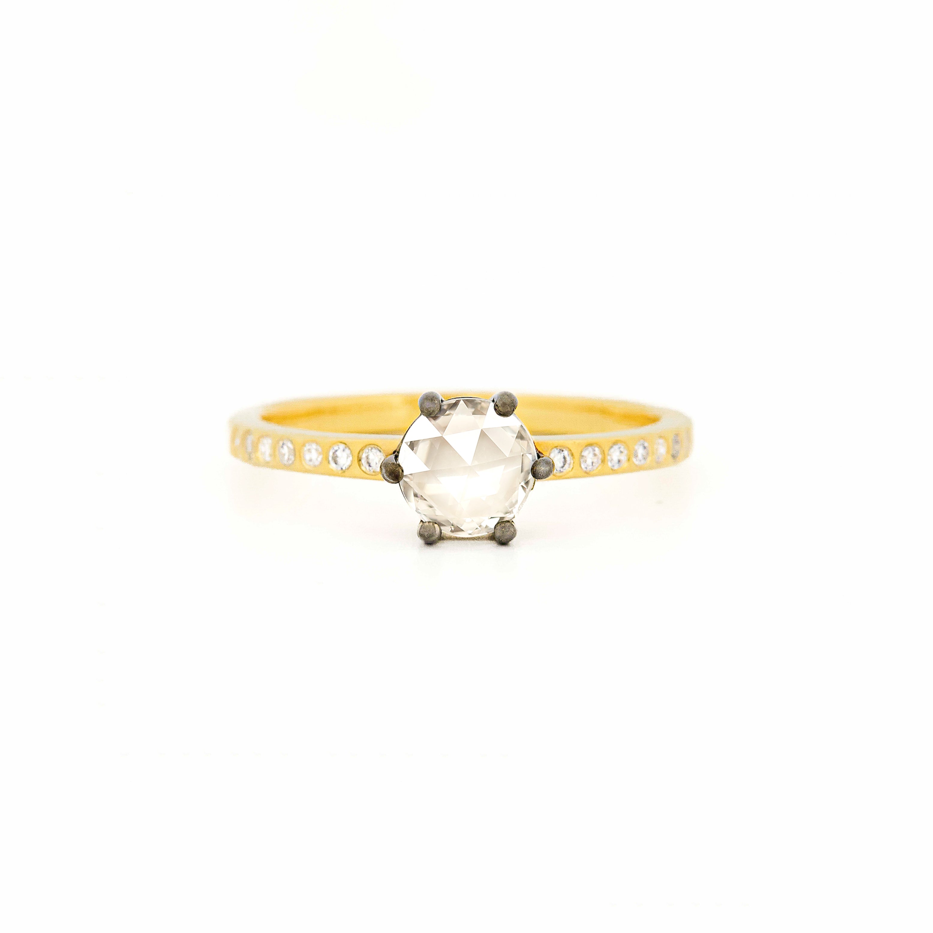 Ring with a large central rose-cut diamond and smaller side diamonds on a yellow gold band against a white background