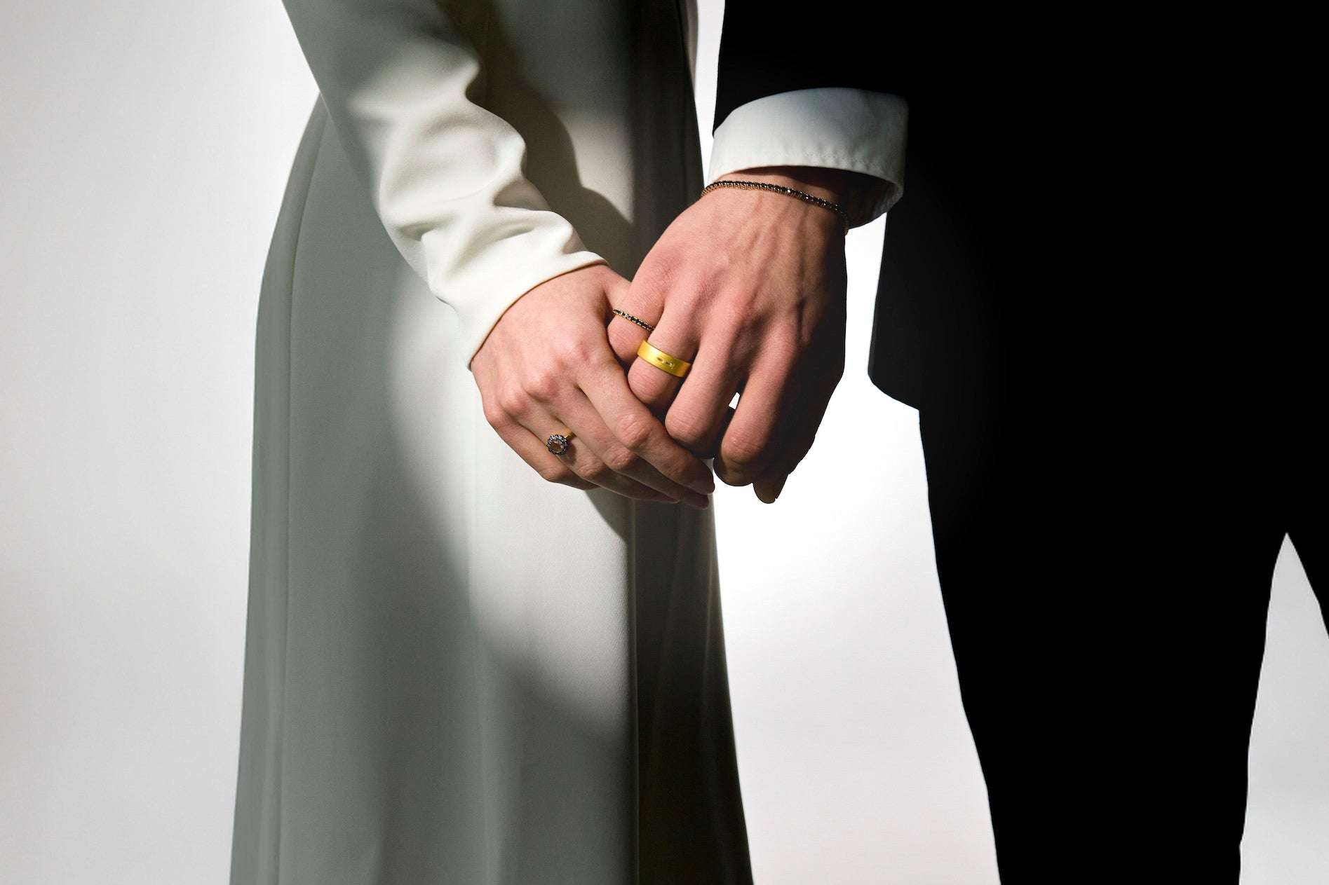 two lovers holding hands on their wedding day, wearing mesmerising gold rings
