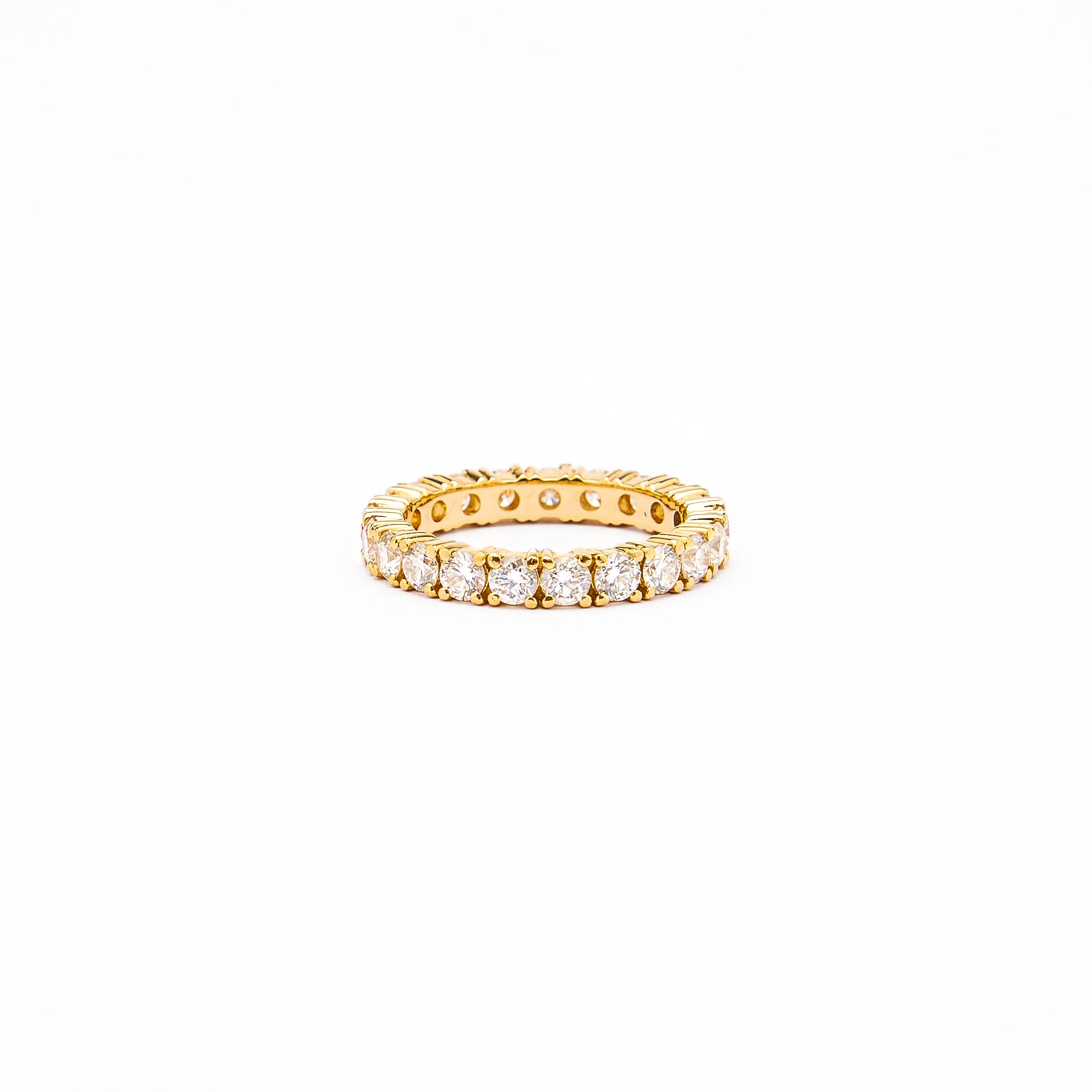 an 18k gold eternity ring with 3mm white diamonds on a white background.