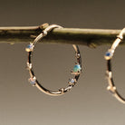 Gold hoop earrings with embedded australian opals and diamonds on a branch