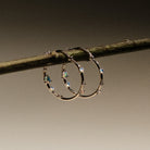 Gold hoop earrings with embedded australian opals and diamonds on a branch