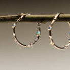 Gold hoop earrings with embedded australian opals and diamonds on a branch