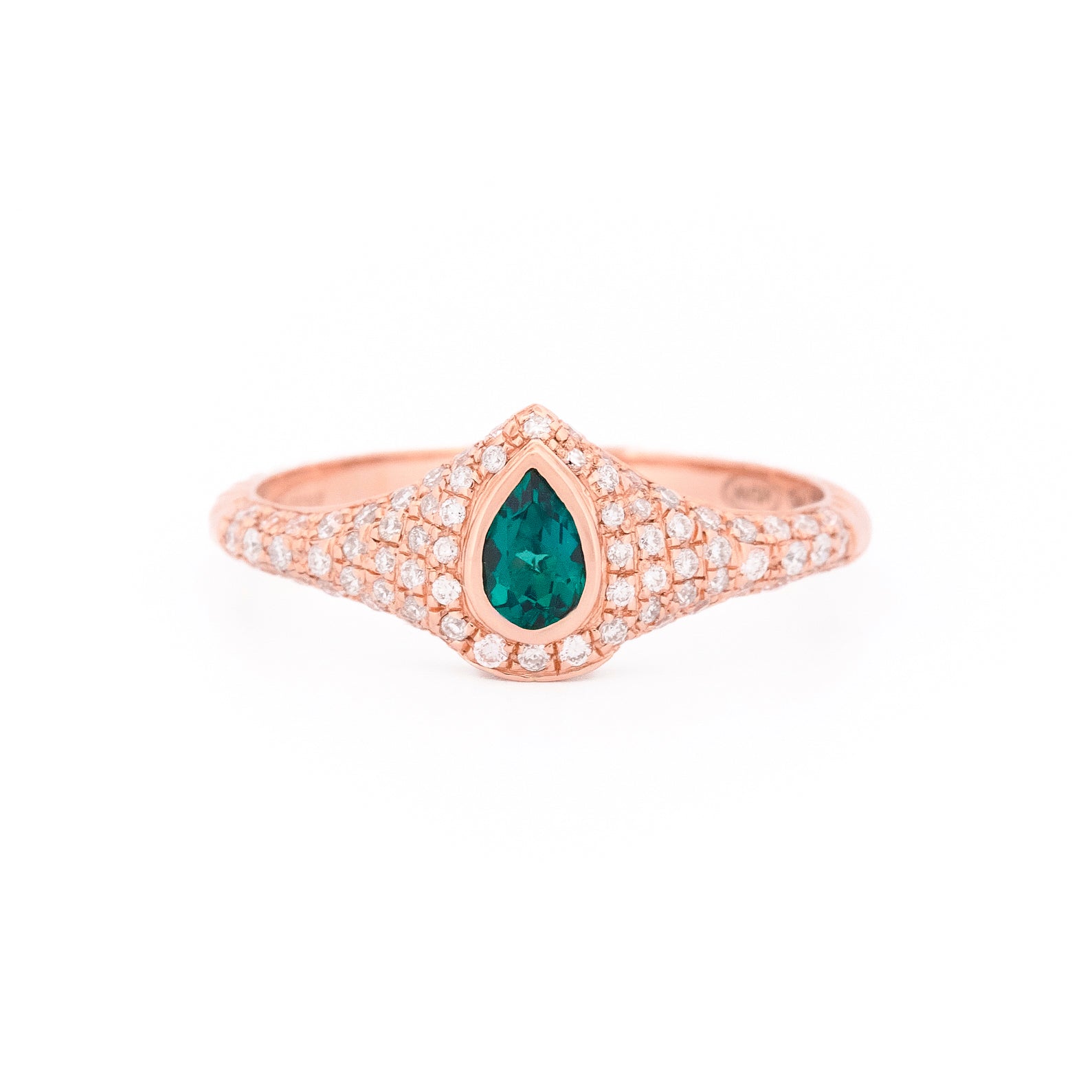 Gold signet ring with a emerald teardrop gemstone and pave diamonds on a white background