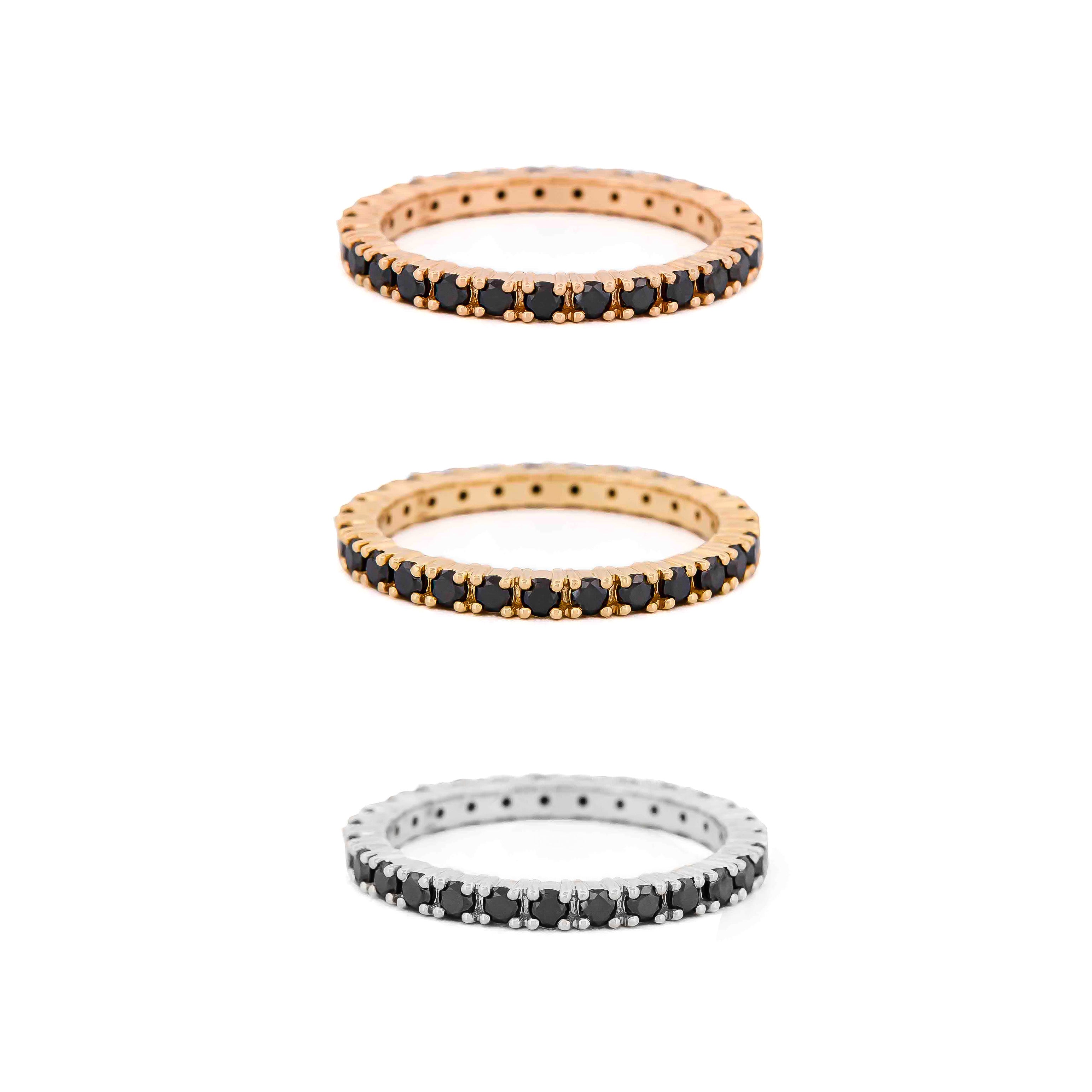 Three yellow, rose gold and white gold eternity rings with black diamonds on a white background