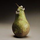 Gold and diamond earrings on a green pear against a dark background.