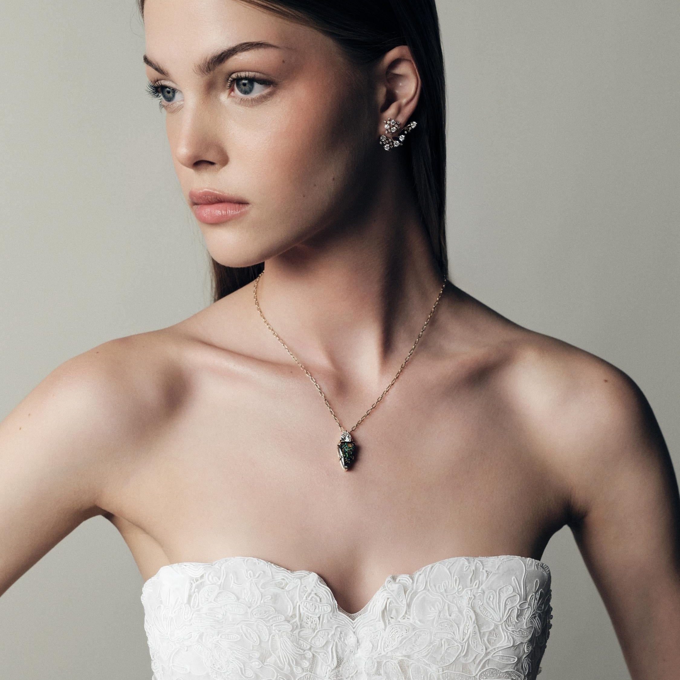 Woman wearing a white strapless dress and gold chain with a koroit australian opal and trillion diamond pendant, against a neutral background