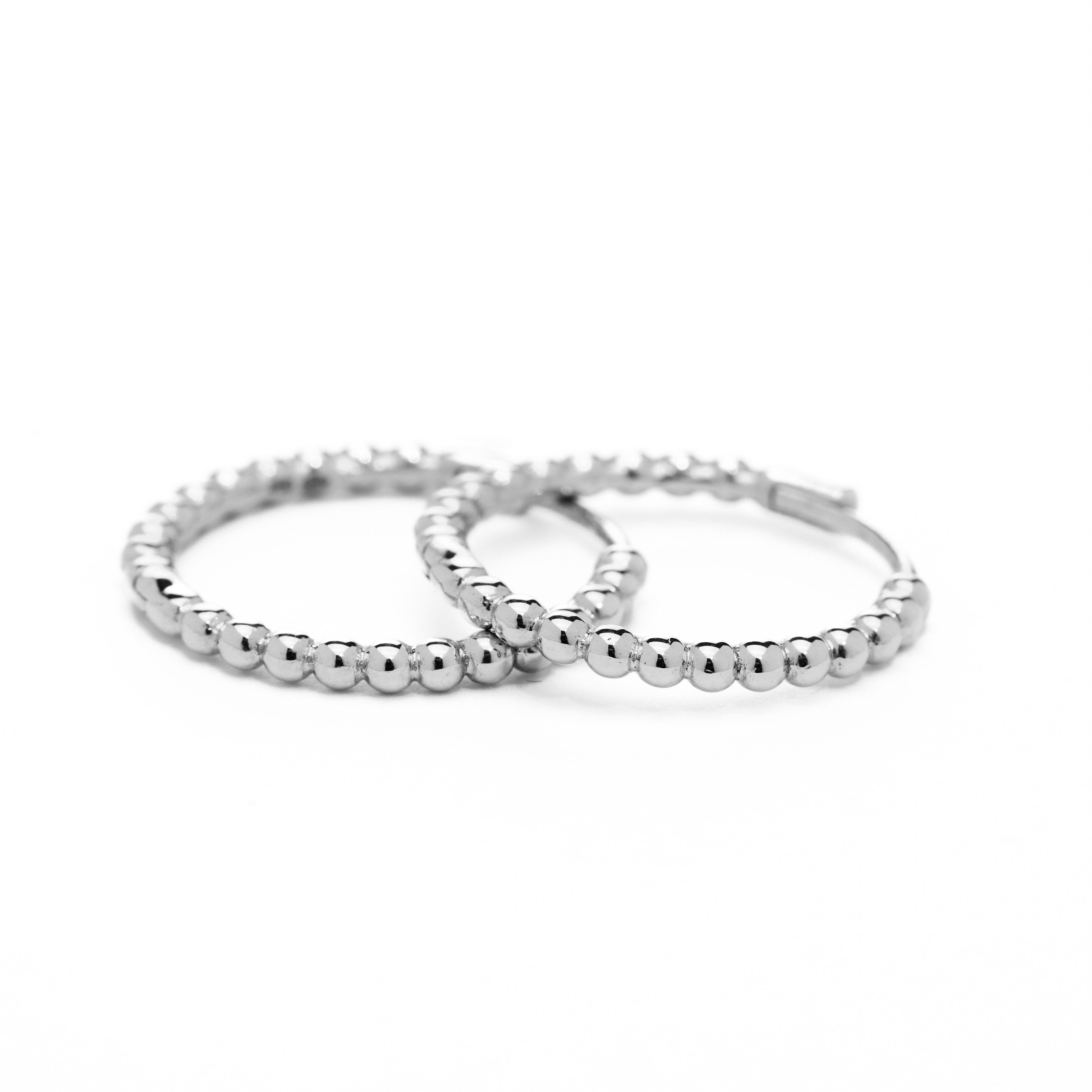 A pair of white  gold hoop earrings with a bubbly design, displayed against a white background.