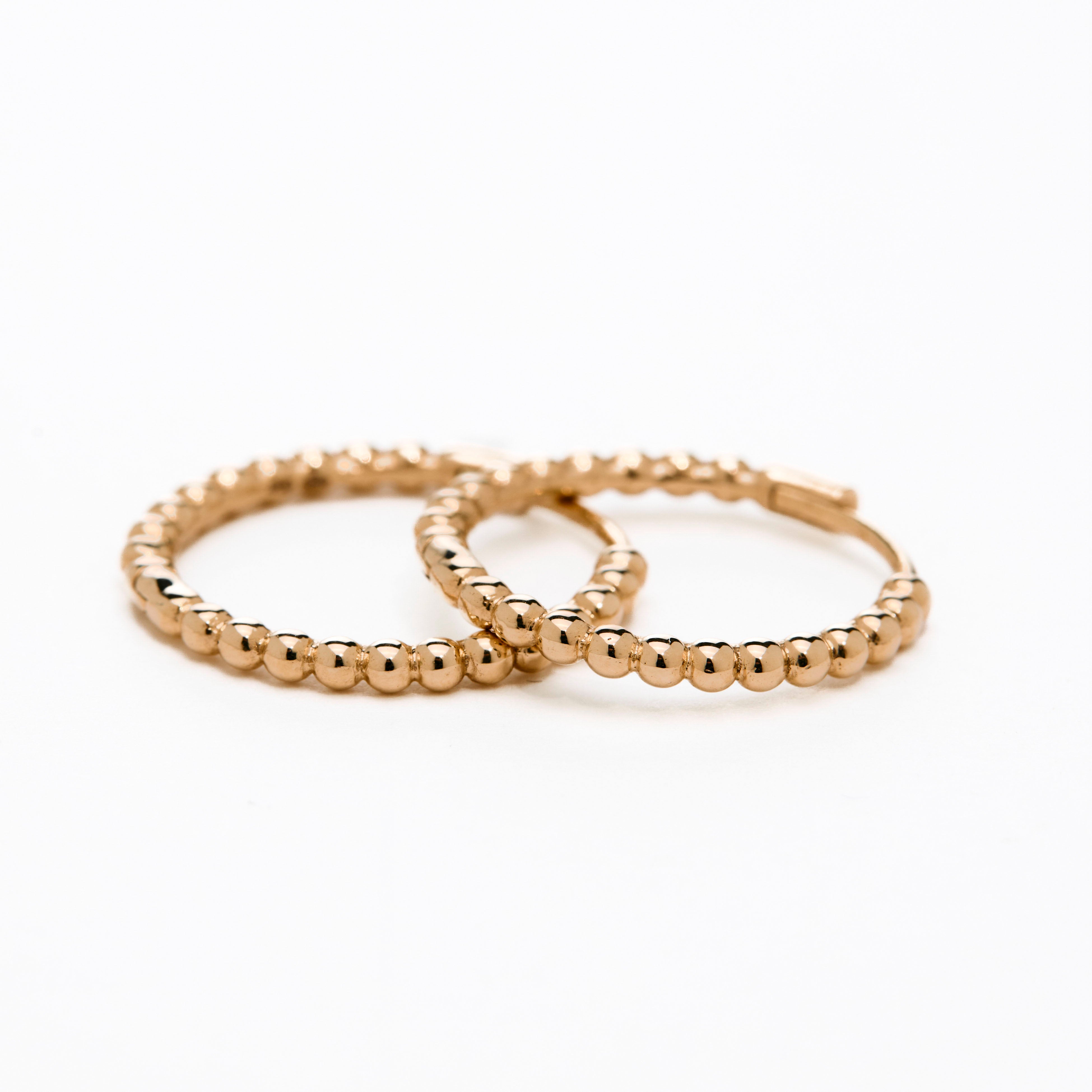 A pair of yellow  gold hoop earrings with a bubbly design, displayed against a white background.