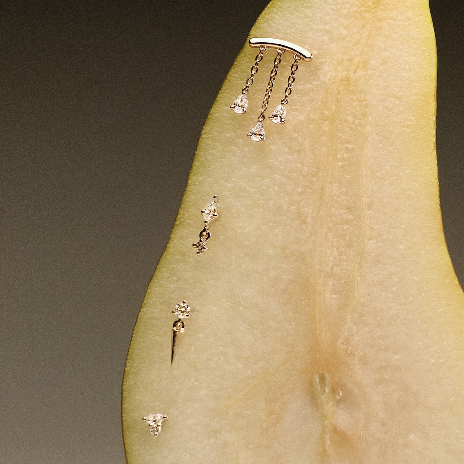 Gold earrings, teardrop diamonds chandelier stud, The Floating Kite Diamond Stud, The Floating Gold Icicle Stud, The Marquise and Round Diamond stud, on a pear with a neutral backgrounda.
