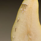 Gold earrings, teardrop diamonds chandelier stud, The Floating Kite Diamond Stud, The Floating Gold Icicle Stud, The Marquise and Round Diamond stud, on a pear with a neutral backgrounda.