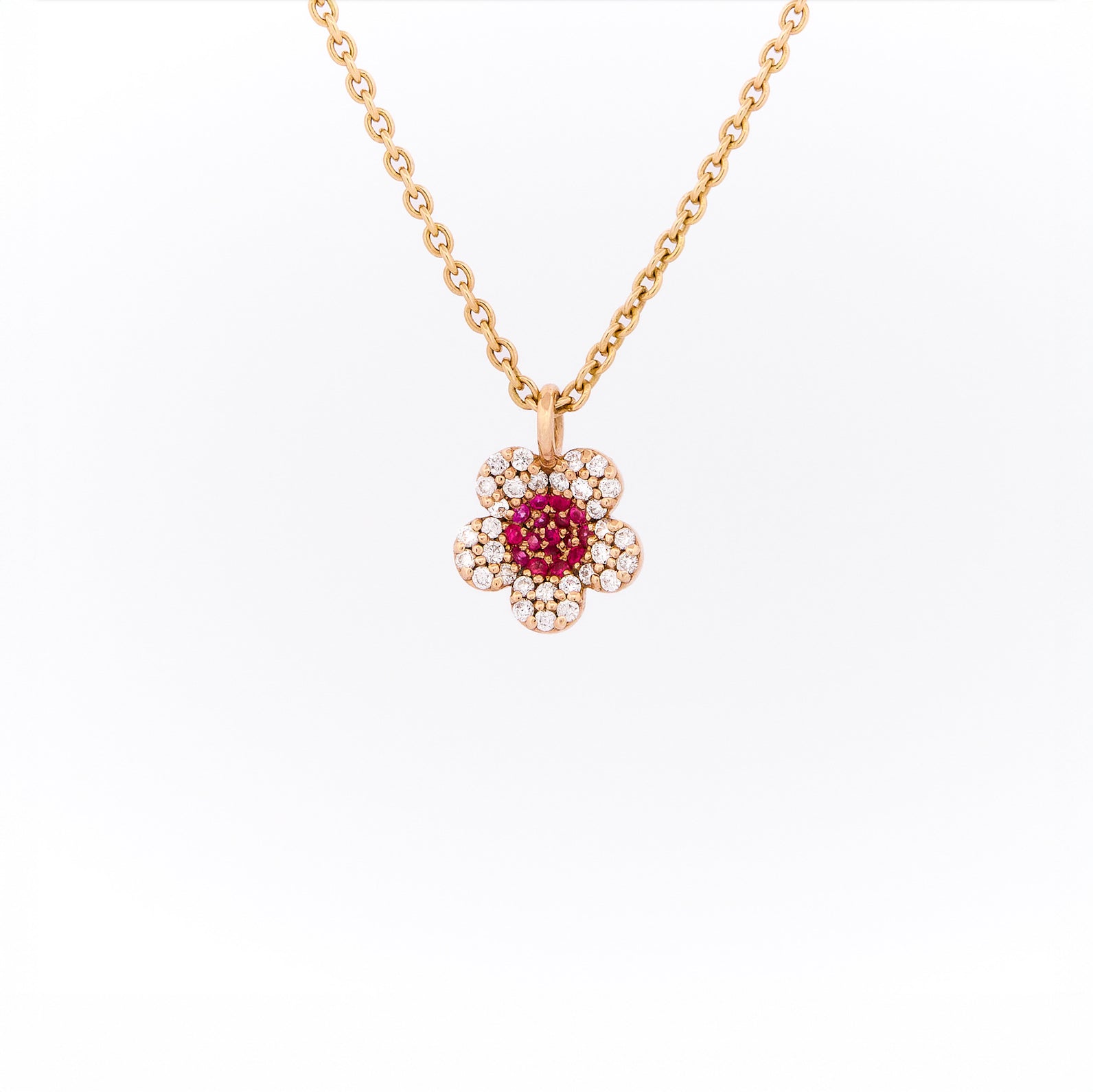 Yellow gold necklace with a flower-shaped pendant featuring rubies and diamonds on a white background