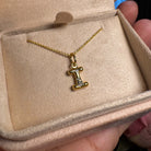 Gold necklace with a 'I' pendant in an open jewelry box.