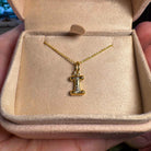 Gold necklace with a letter 'I' pendant in an open jewelry box.