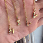 Gold necklaces with letter pendants on a hand