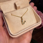 Gold necklace with a 'V' pendant in a beige jewelry box held by a hand.