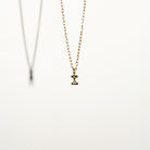 Gold necklace with a small I letter pendant on a white background