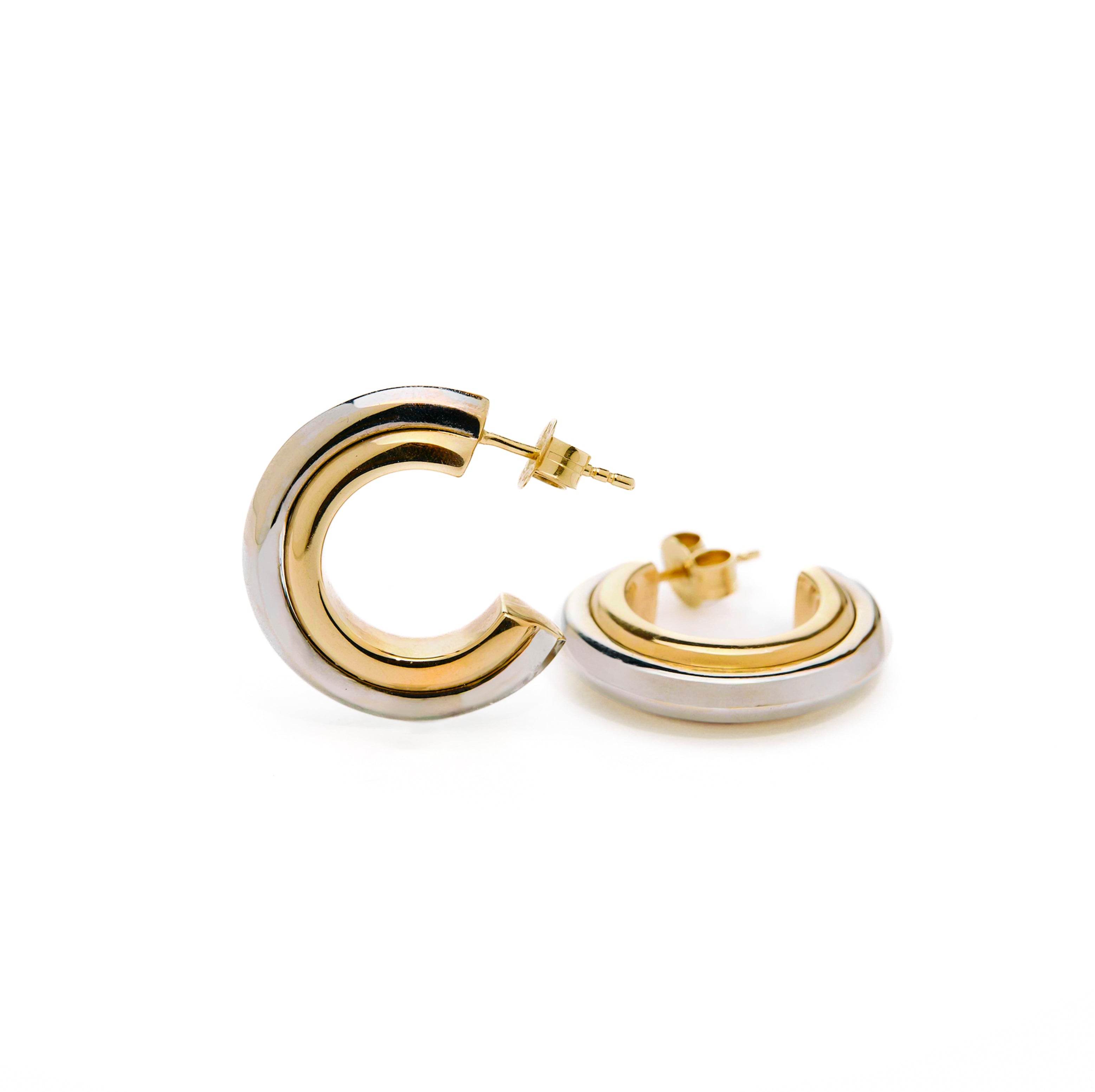 Pair of thick hoop earrings with gold and white gold design on a white background