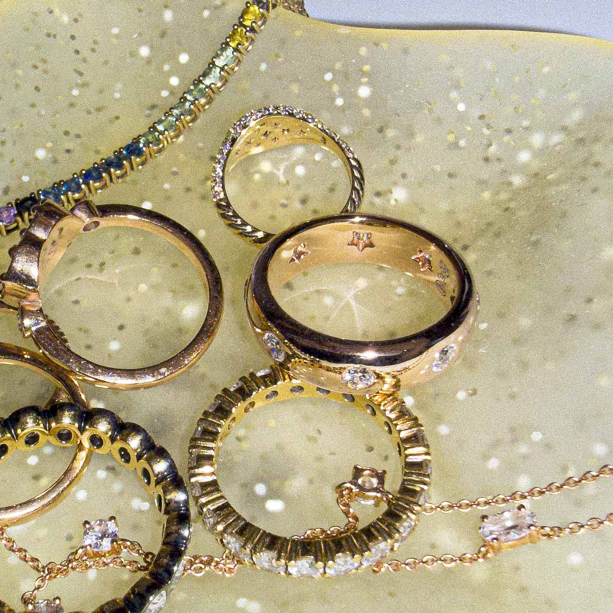 gold rings on a jewelry tray, one band has stars behind the diamonds setting. 