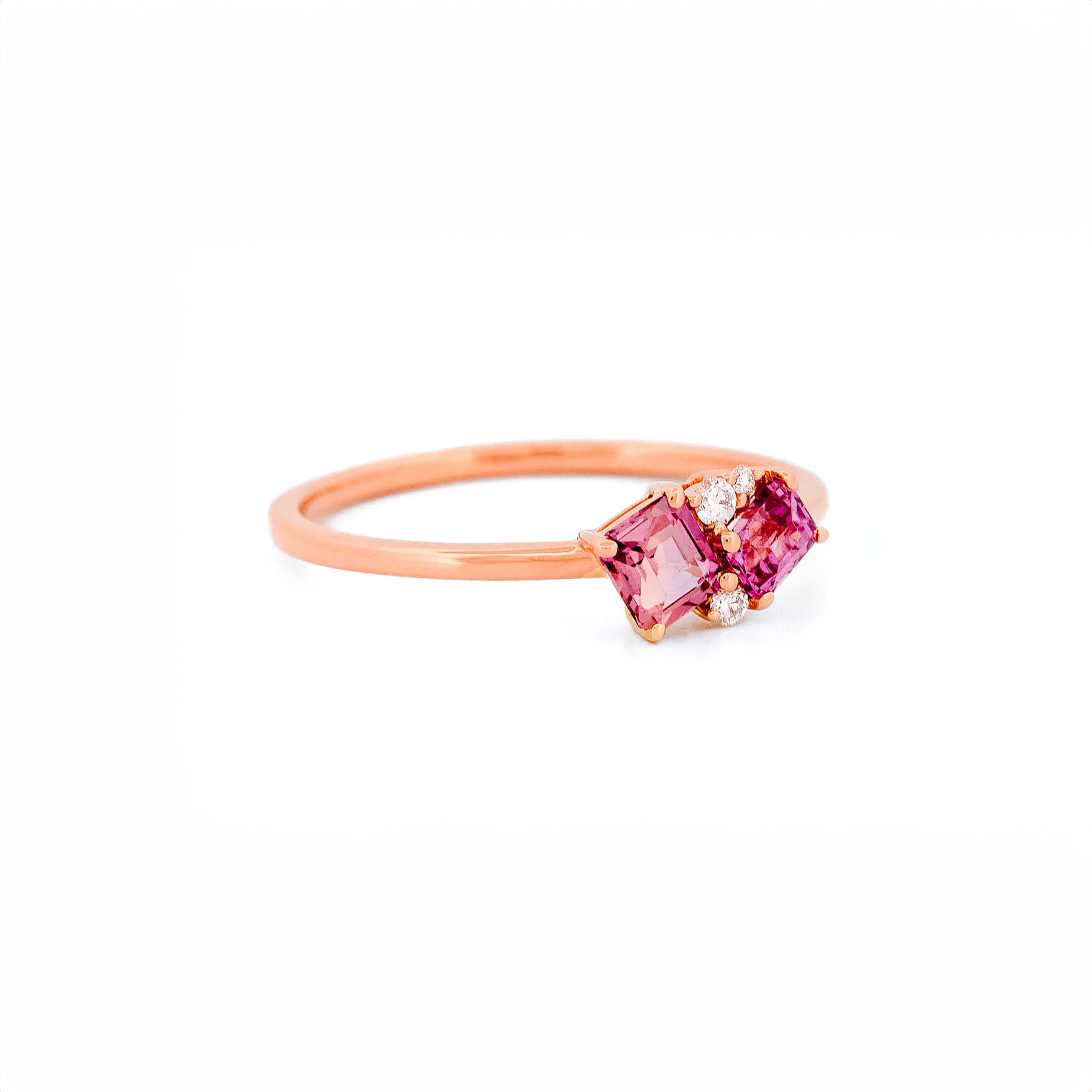 Gold ring with two pink sapphires and diamonds accents on a white background
