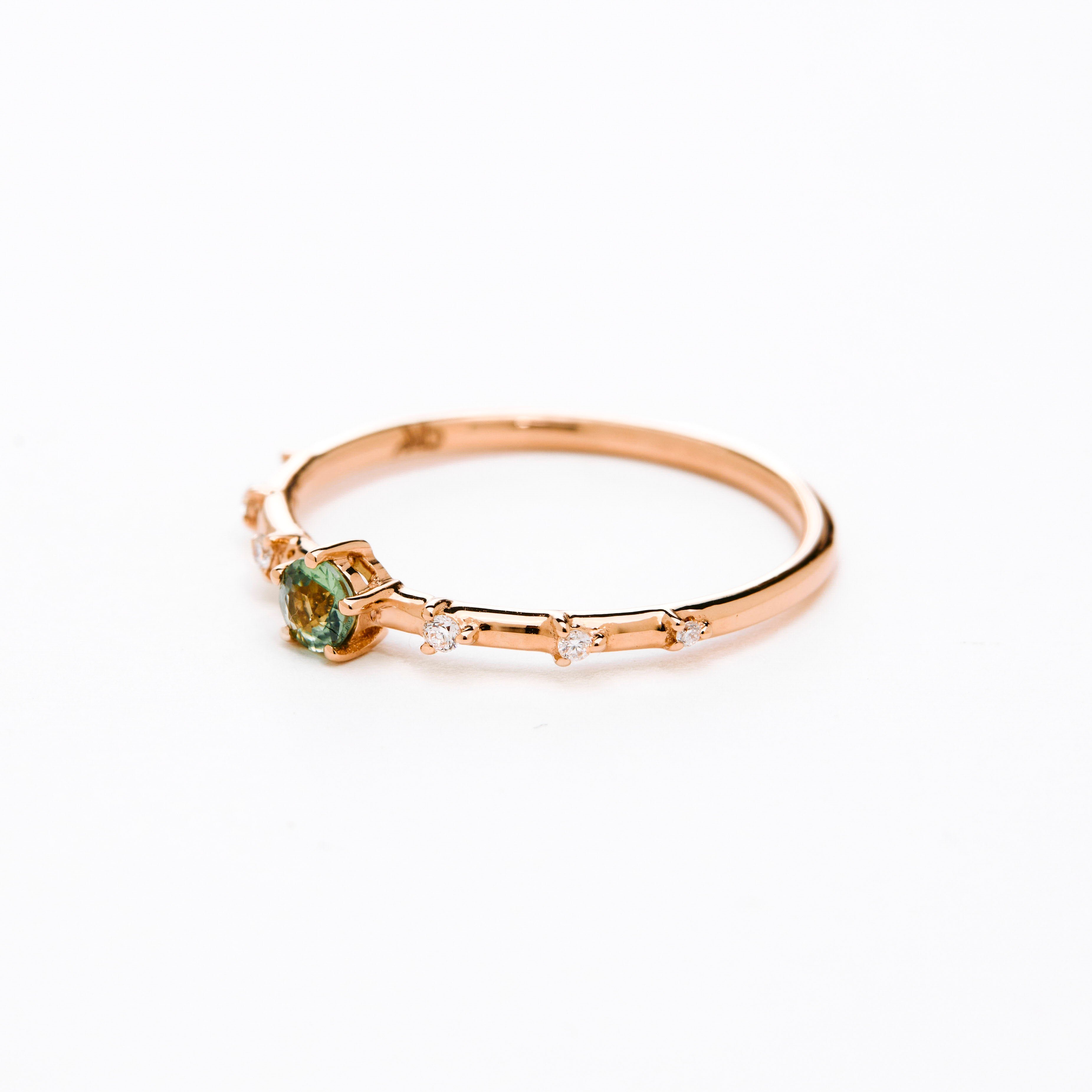 A gold band ring featuring a central sapphire with smaller diamond accents around it, presented against a white background.