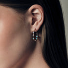 Gold hoop earrings with embedded Australian opals and diamonds on a ear.