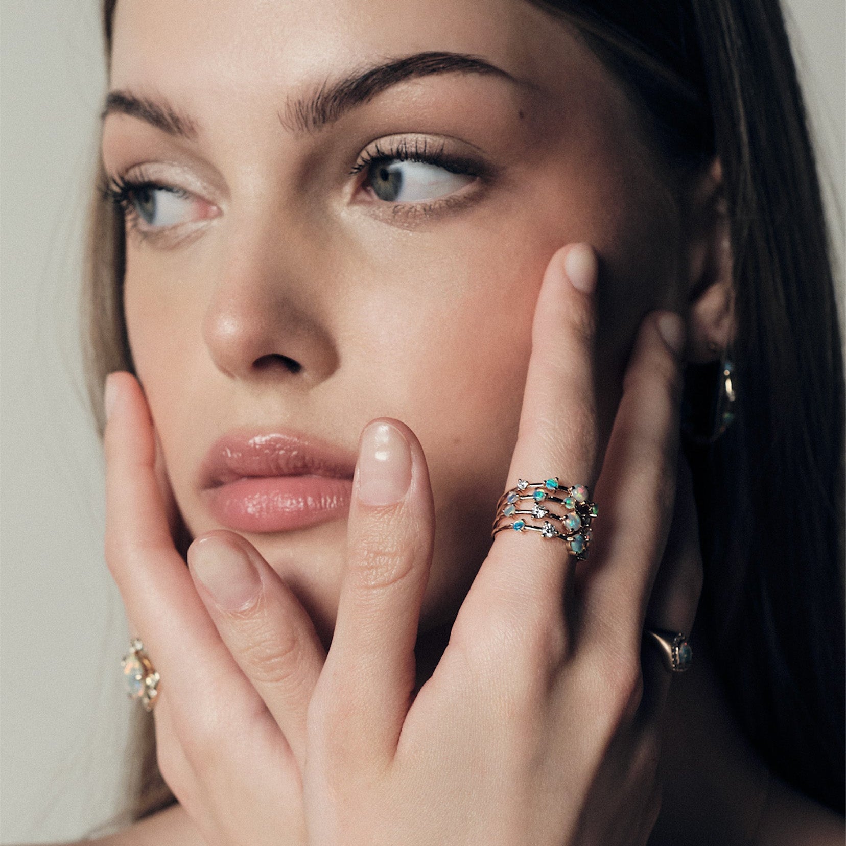 Woman wearing stackable Australian Opals and Diamonds Dew Drops Collection, with a visible Australian Opals, close-up of face and hand.