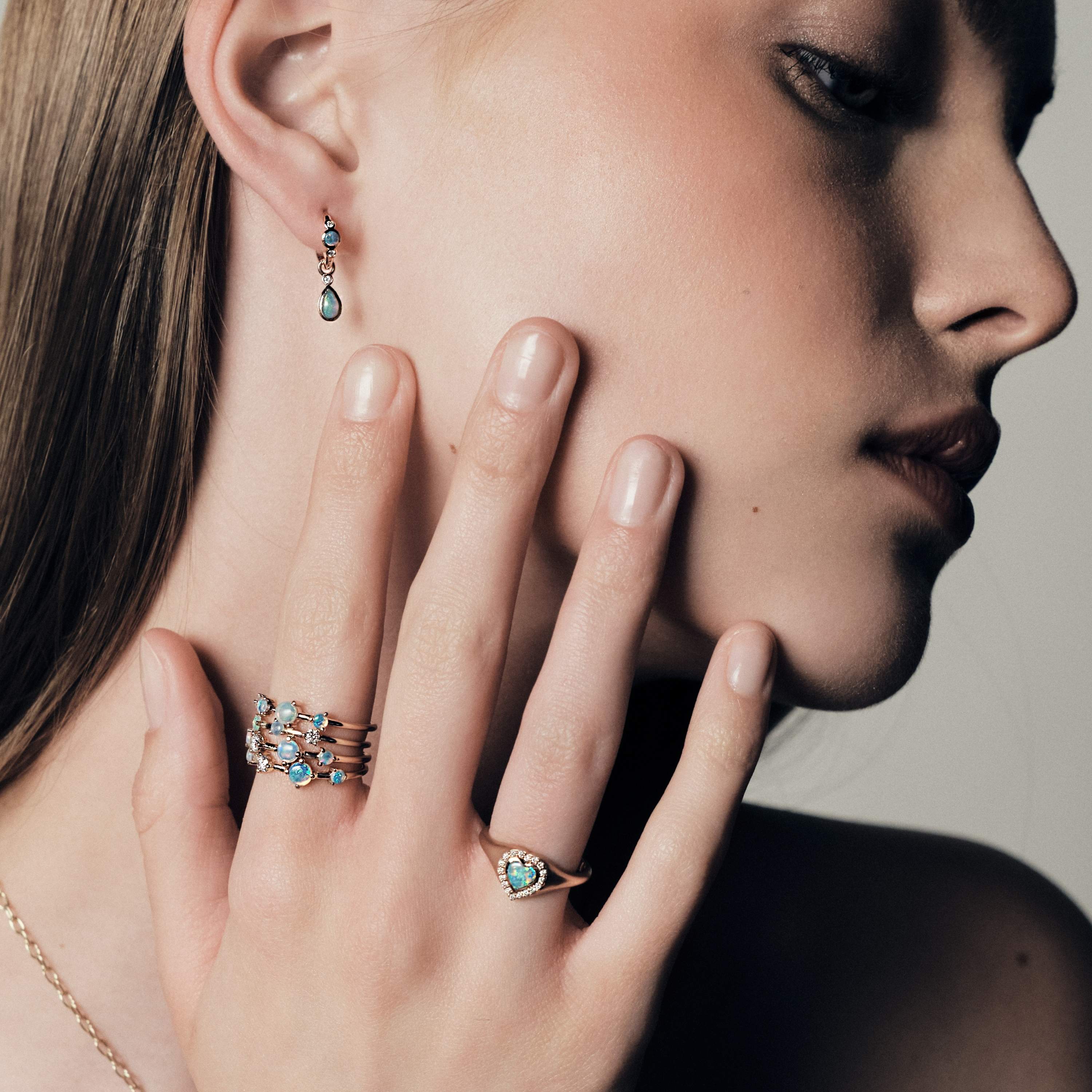 Woman wearing stackable Australian Opals and Diamonds Dew Drops Collection, with a visible Australian Opals, close-up of face and hand.