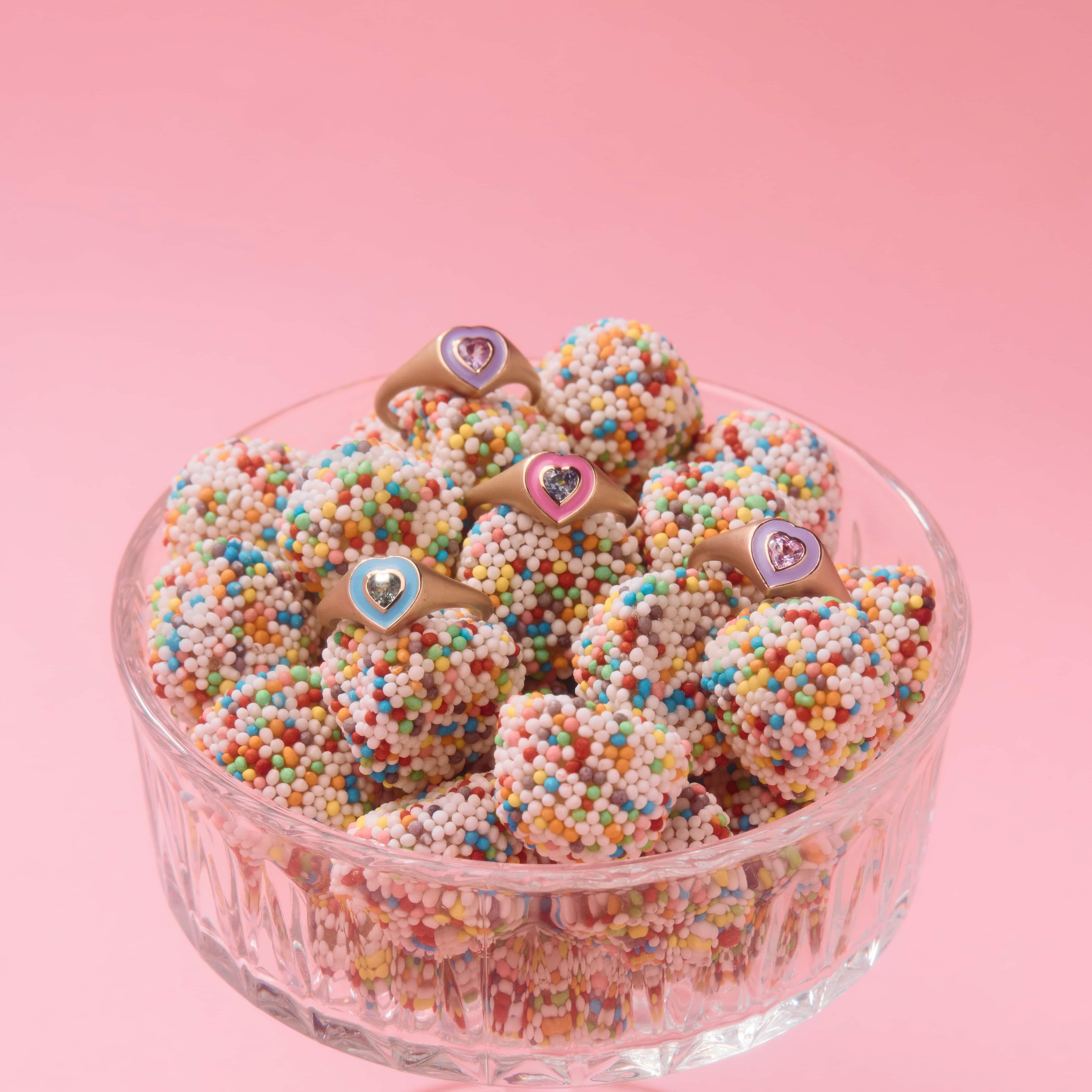 colorful enamel rings with sapphire accents in a bowl of candy