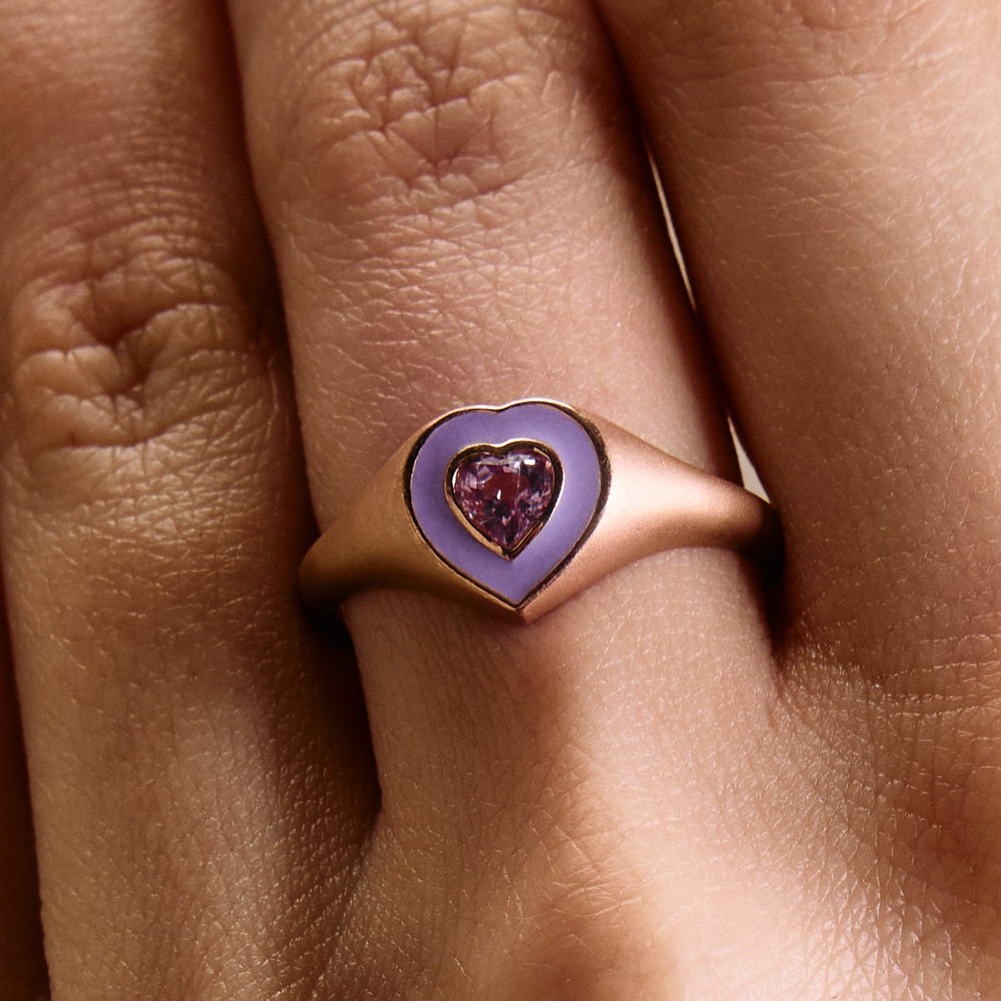 a colorful purple enamel ring with middle sapphire heart on hand