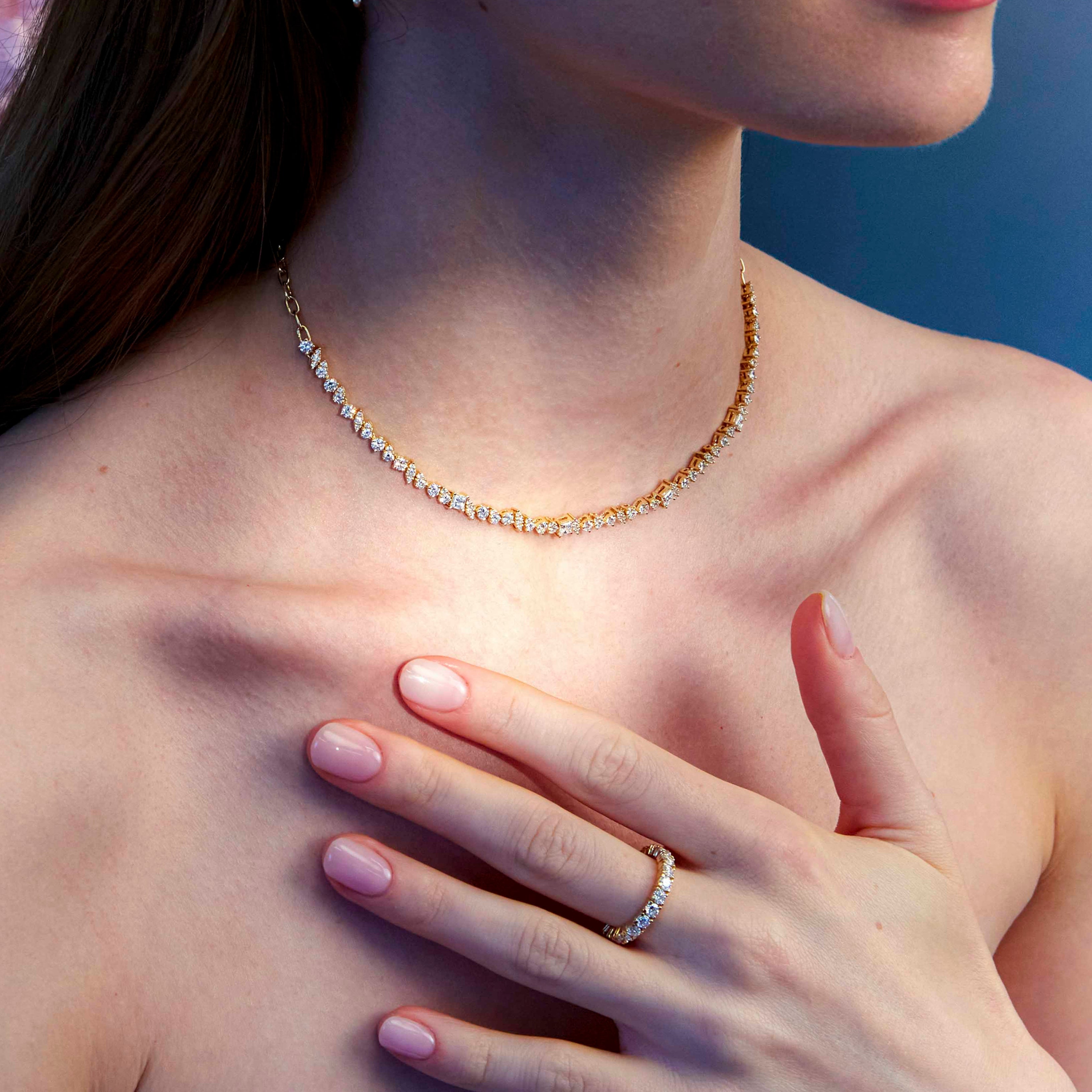A woman wearing a half tennis diamonds necklace and a diamond eternity ring.