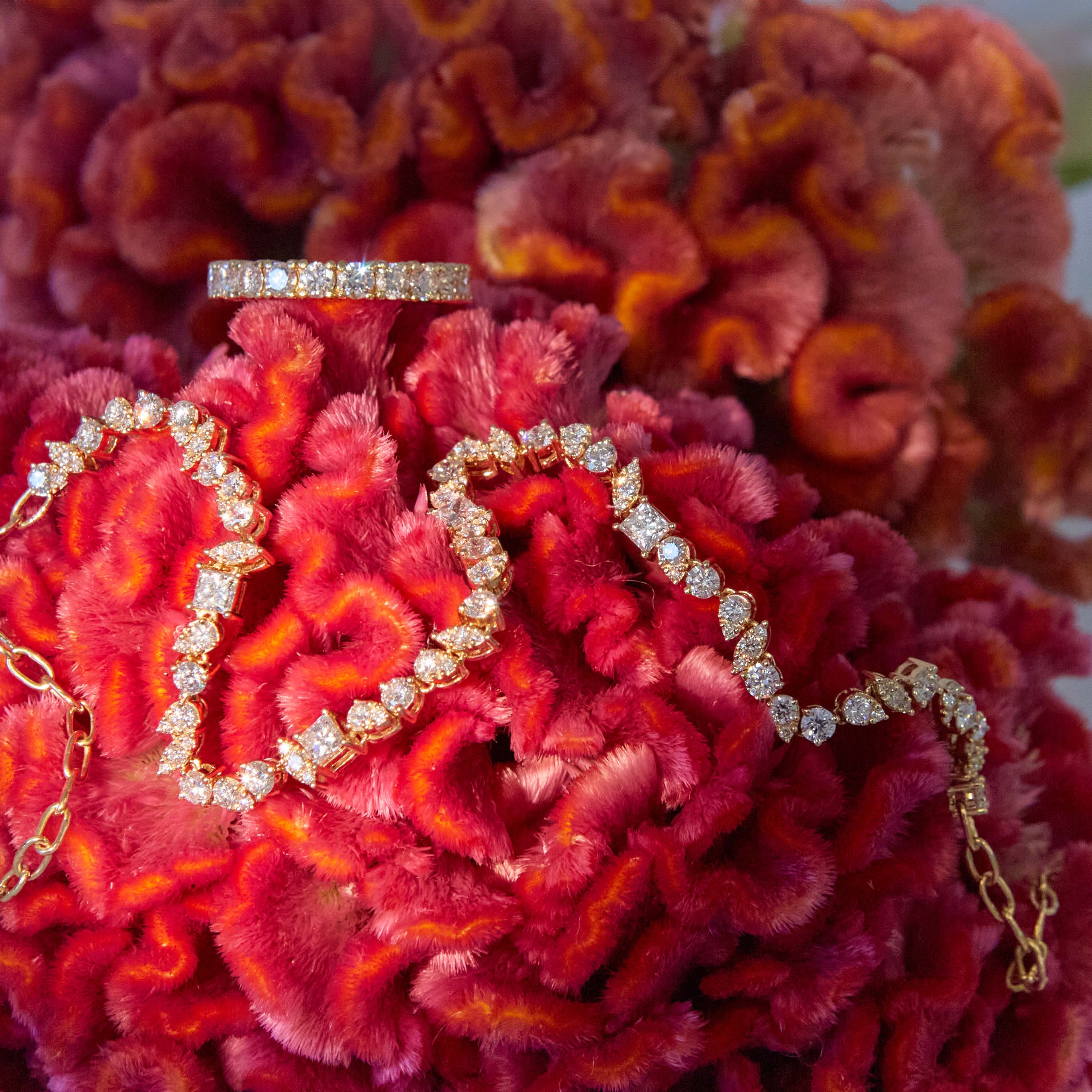 An 18k gold diamond-adorned half tennis choker necklace and a diamond tennis ring on a red flower