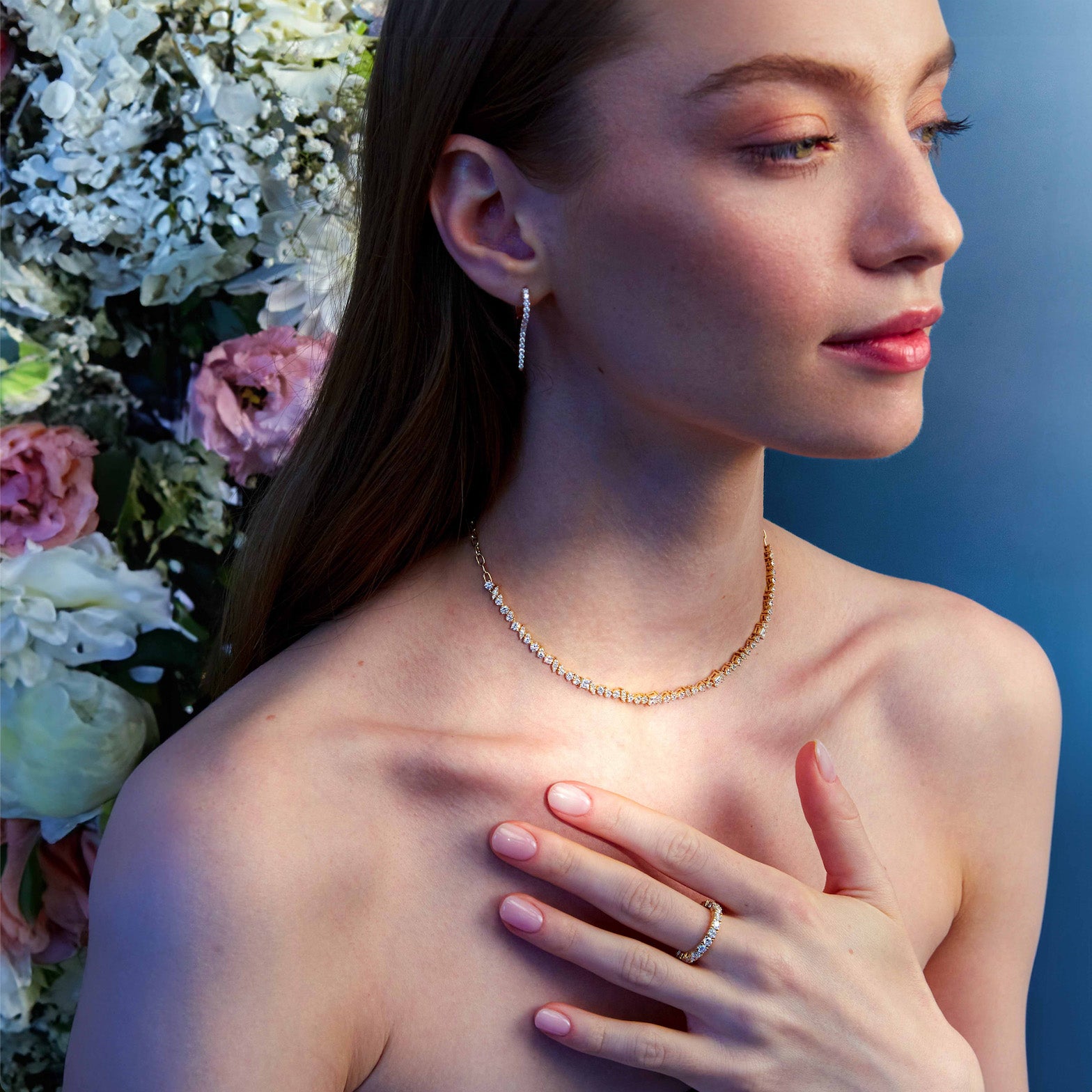Beautiful woman wearing icicles diamonds earrings, a mixed shaped diamonds choker and an eternity diamond ring, with beautiful flowers in the back. 
Femeie superbă care poartă o pereche de cercei cu diamante, un colier choker cu diamante de diferite forme și un inel eternity cu diamante, pe un fundal superb de flori.