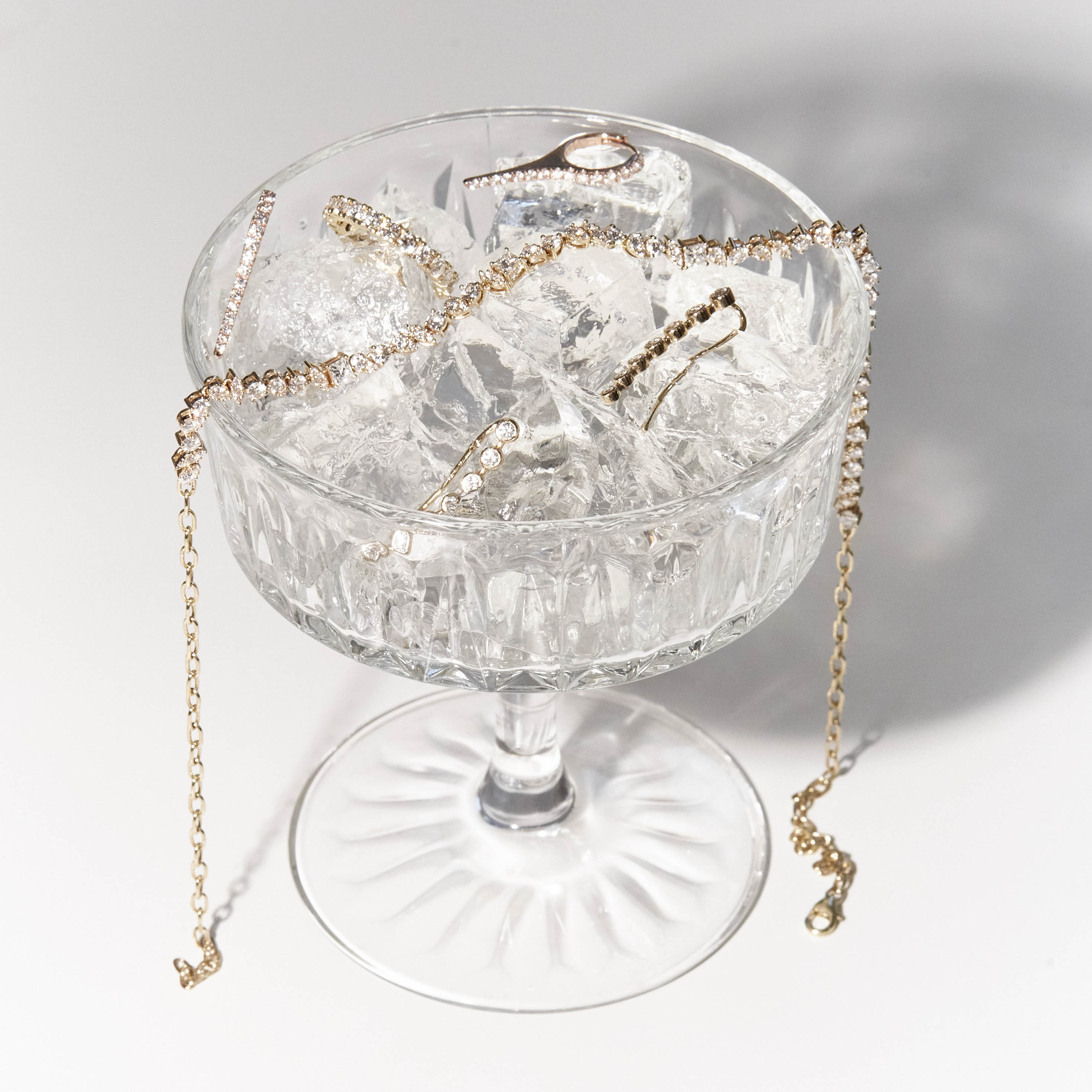 a glass of ice and diamond jewelry, earrings, tennis diamond ring and tennis diamond choker